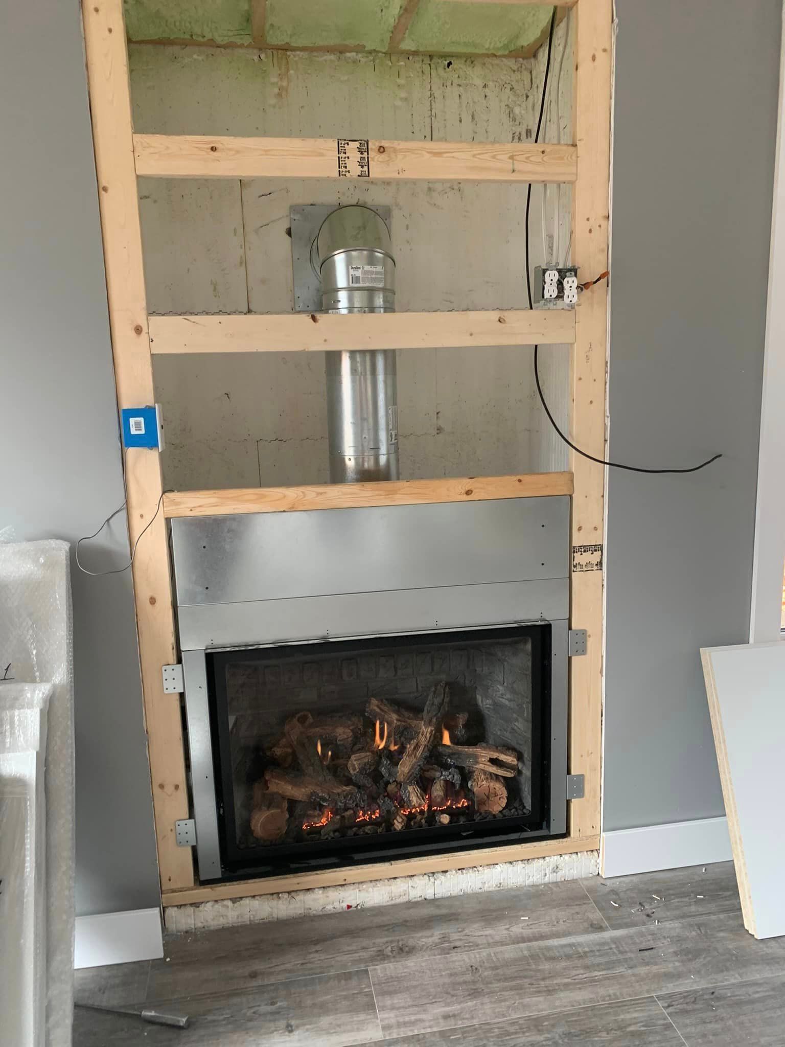 Fireplace under construction, framed with wood, with a metal firebox.