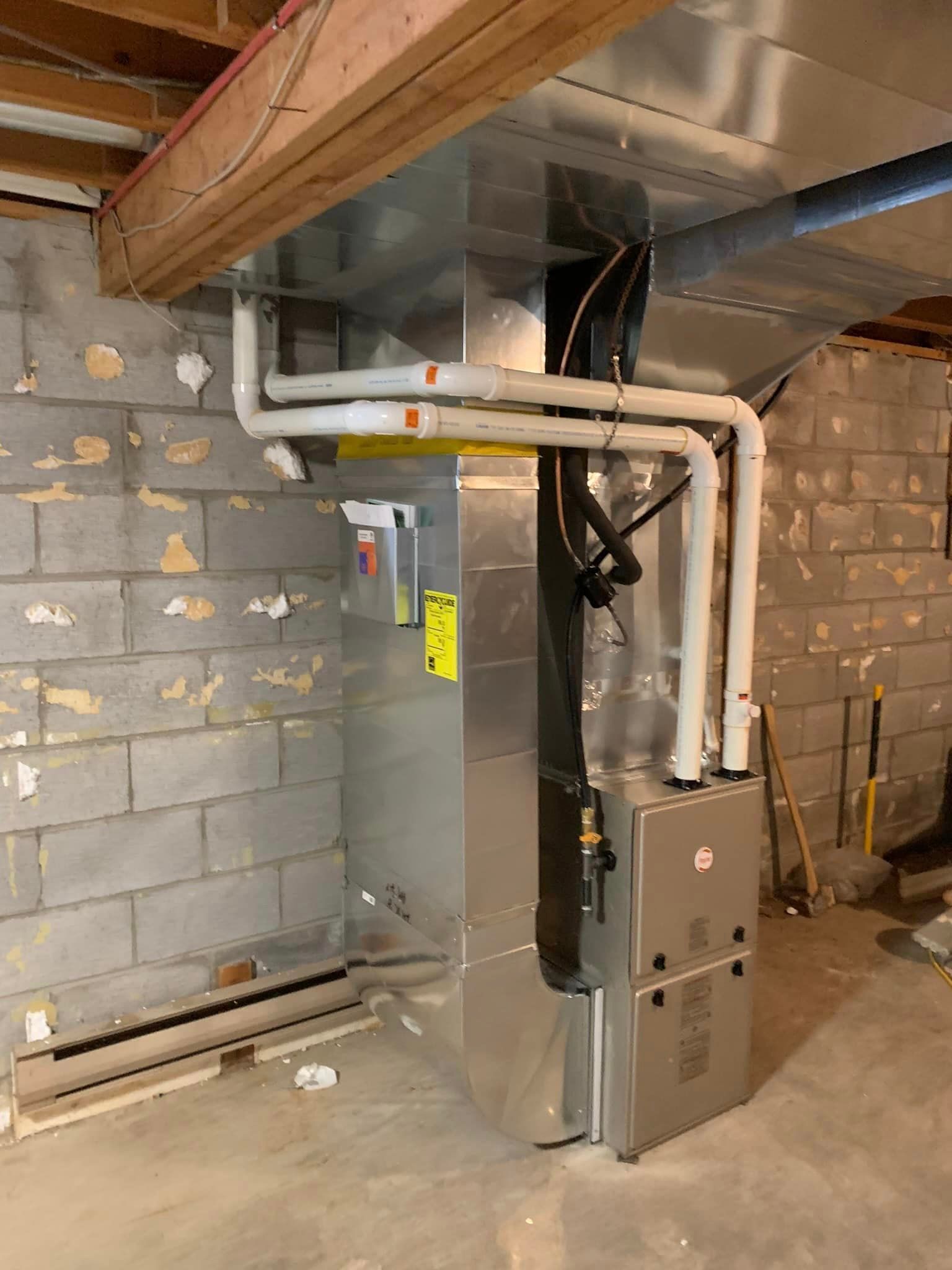 A furnace installed in a basement, with vent pipes attached to it and the wall.