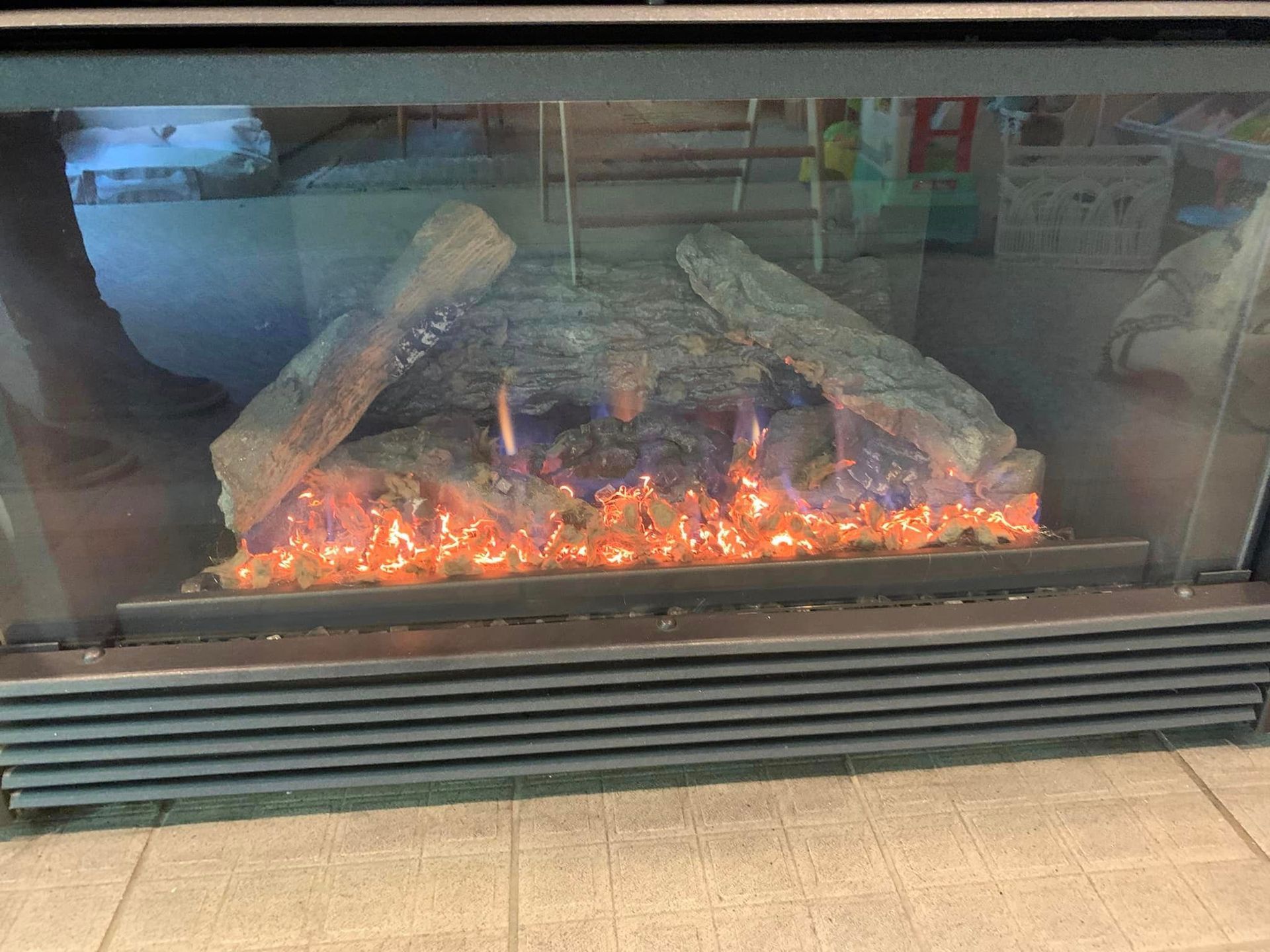 Electric fireplace with faux logs and flickering orange and blue flames.
