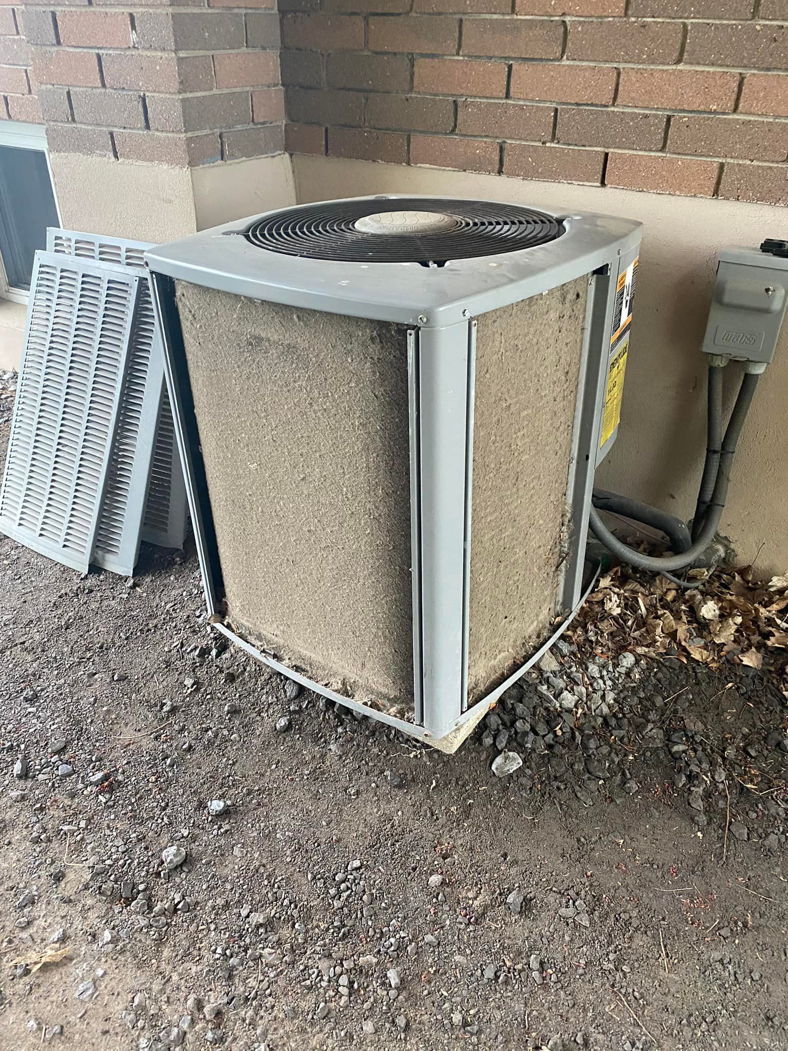 Outdoor air conditioning unit, dirty filter, brick wall, and electrical components.