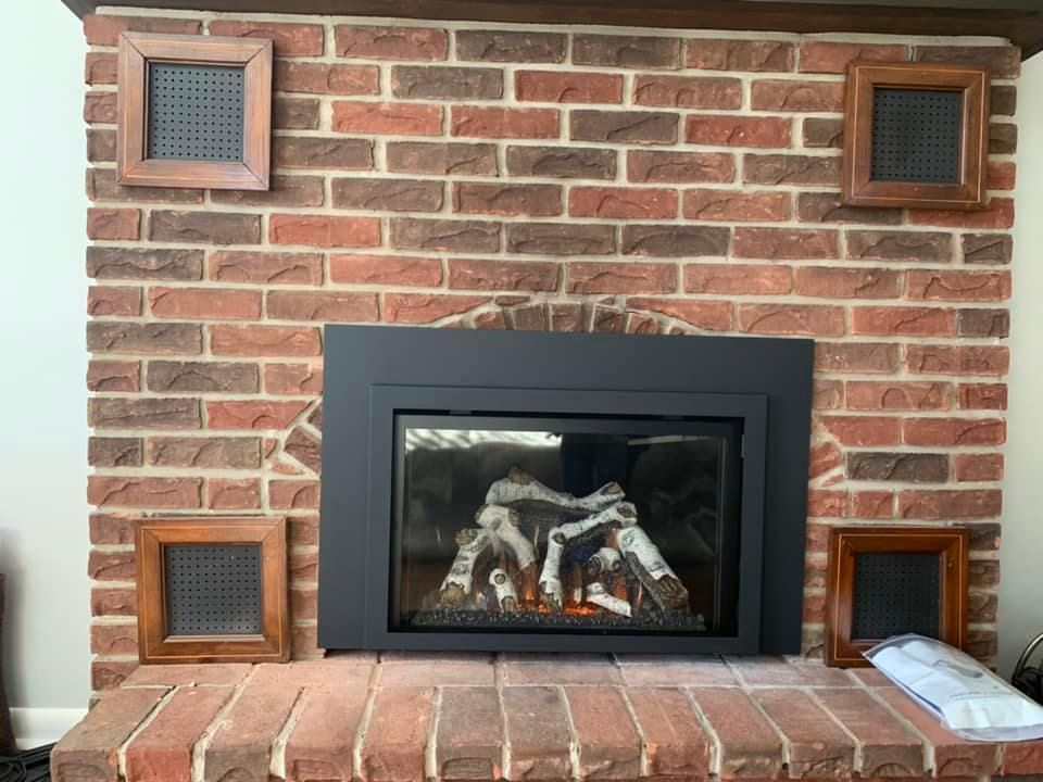 Brick fireplace with black inset, four wood-framed vent covers.