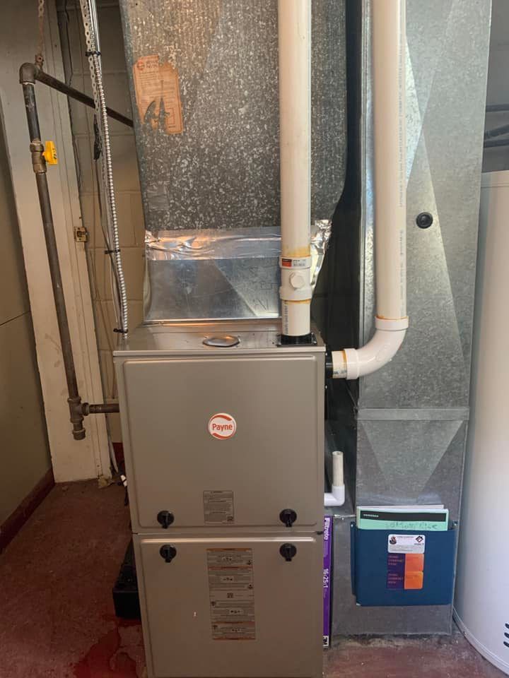 A gas furnace with connected ductwork, pipes, and a water heater in a basement.