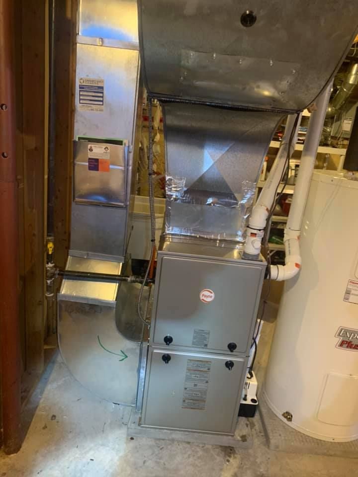 Furnace unit with ductwork and water heater in a basement.