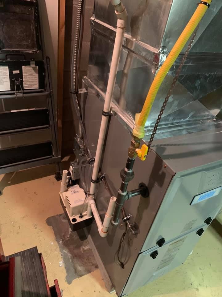 Furnace with gas line and condensate pump in a basement.