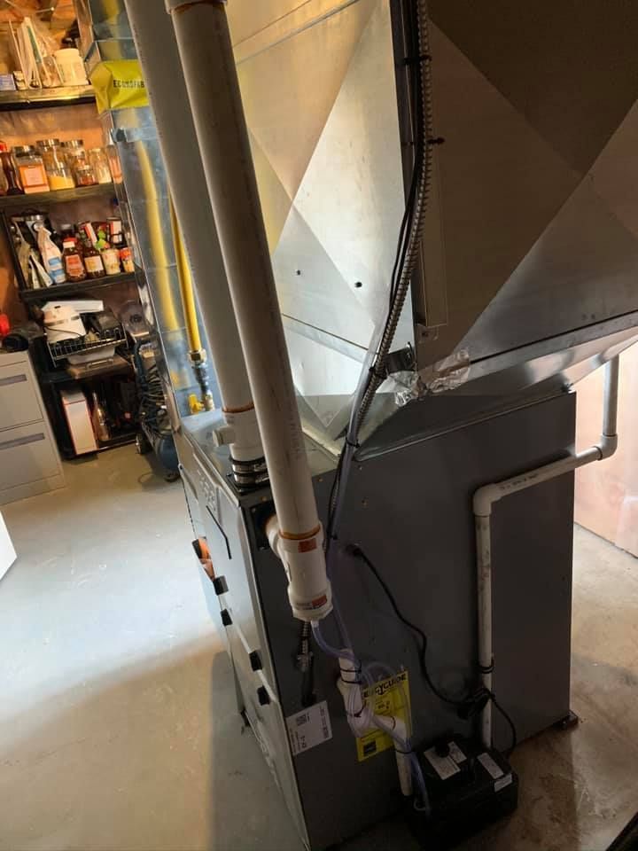 Furnace with vent pipes in a basement setting. Electrical wiring and a condensation pump are visible.
