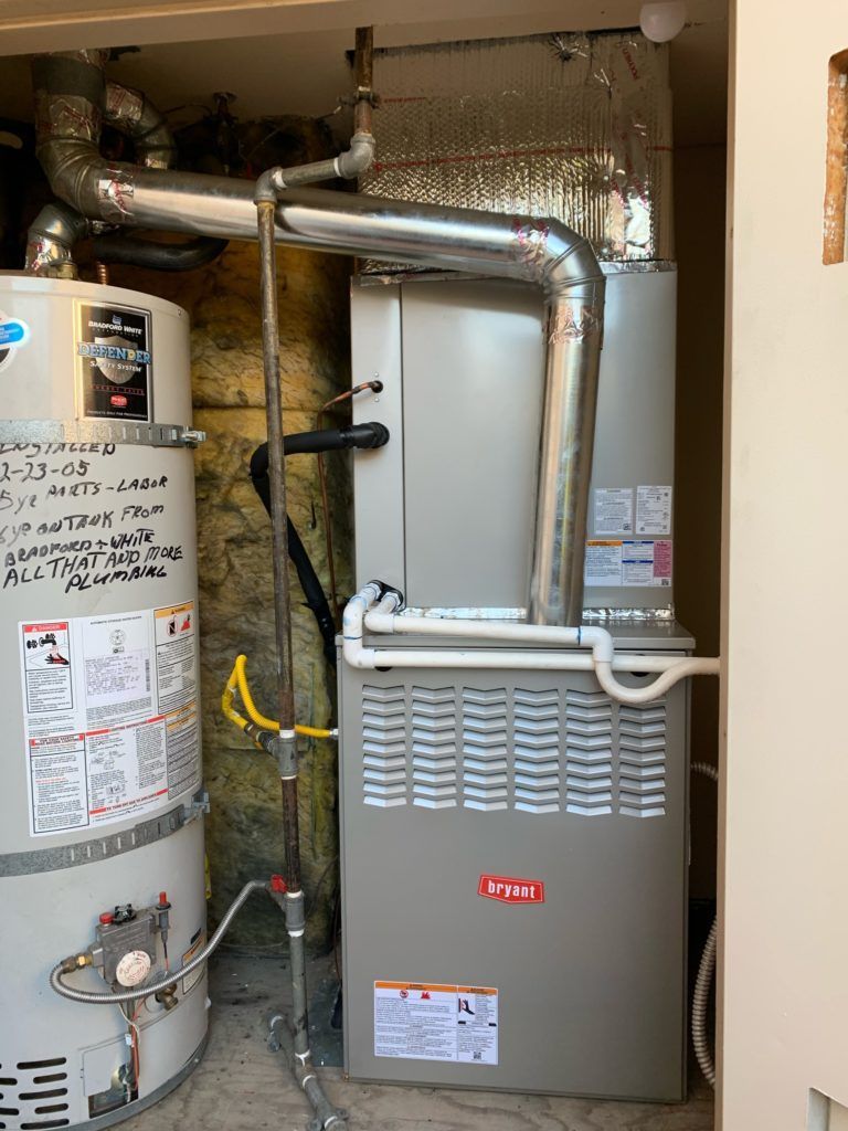 A furnace and water heater are installed in a utility closet with ductwork.