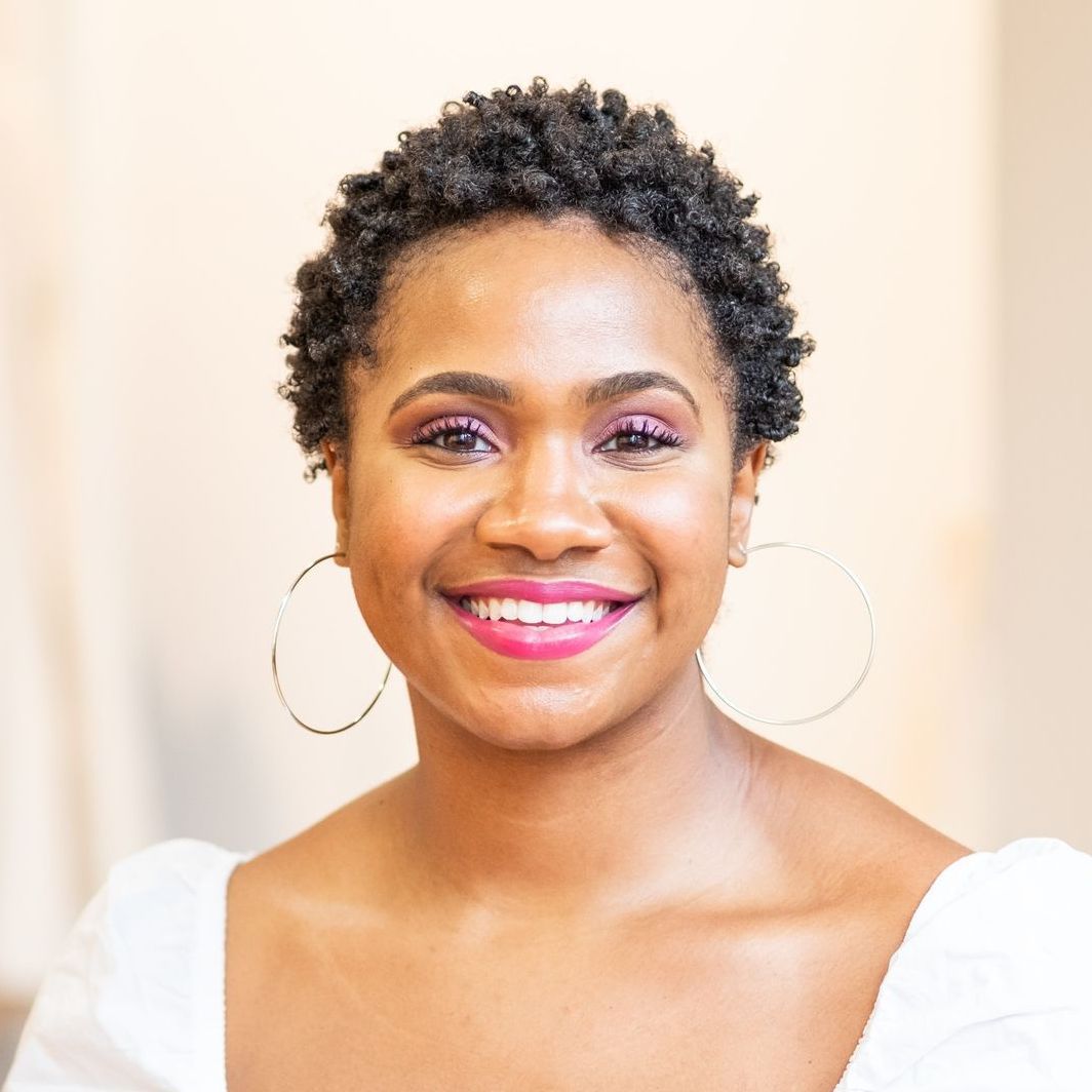 A woman wearing hoop earrings and a white shirt is smiling for the camera.