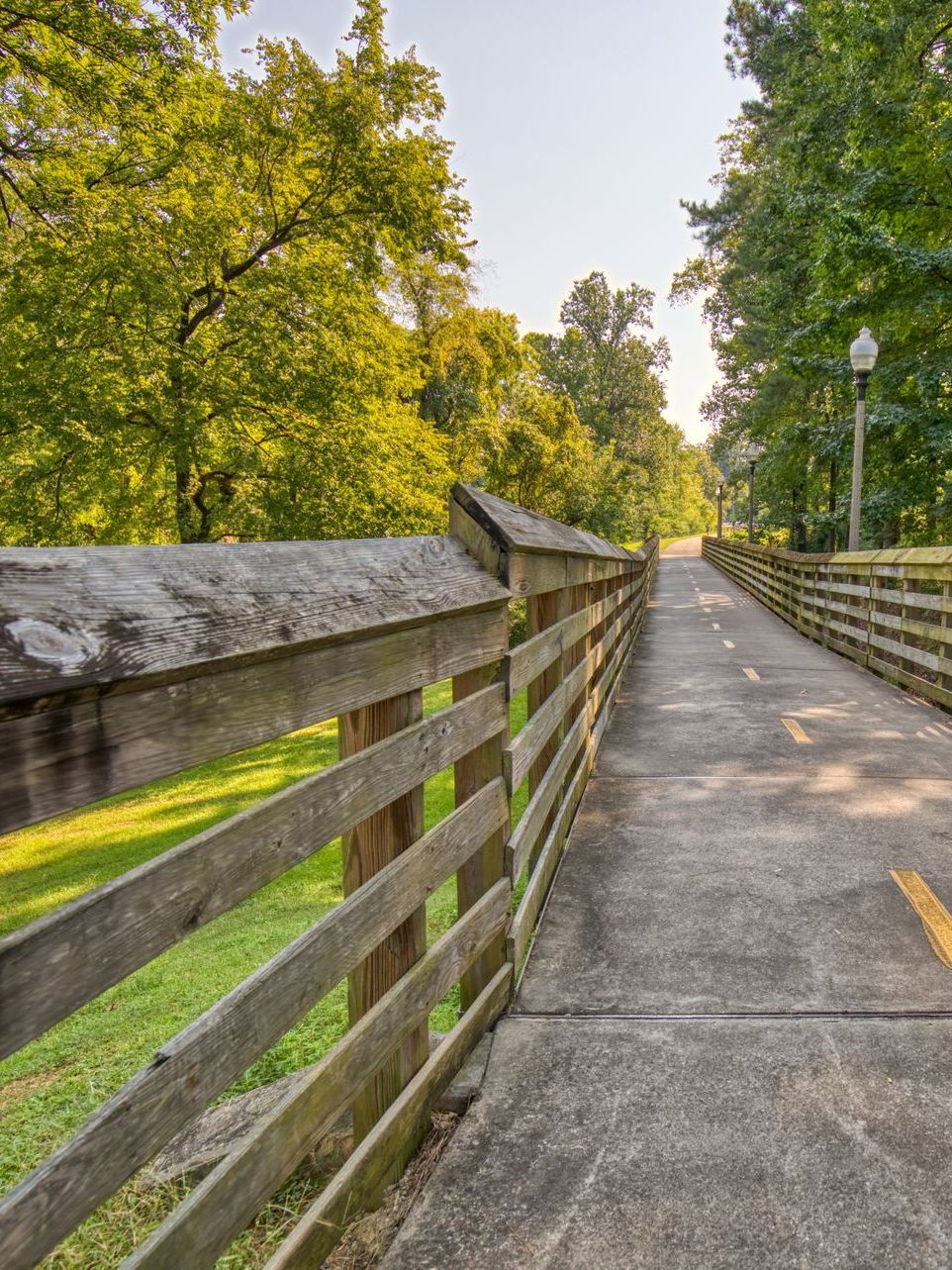 A wooden walkway leading to a gazebo overlooking a body of water at sunset.