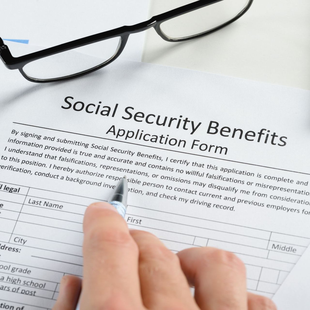 A person is filling out a social security benefits application form