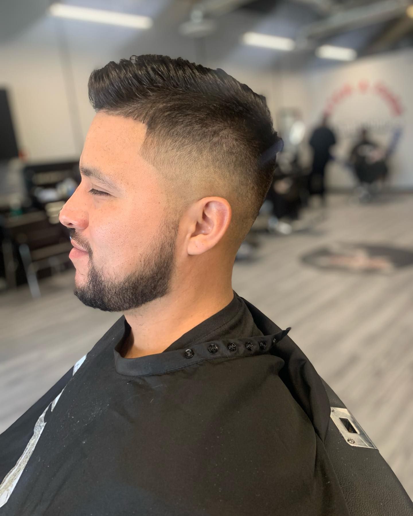 Man with a faded haircut and beard in a barber shop.