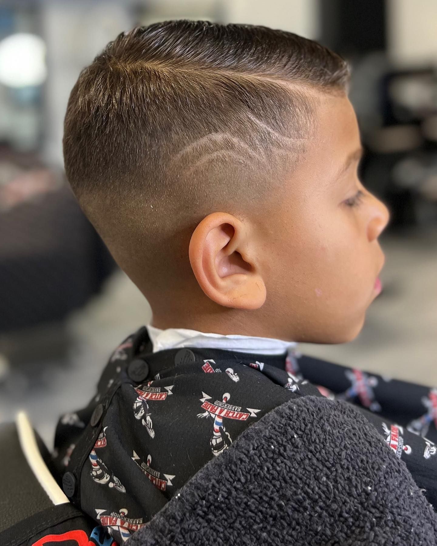 Boy with a fade haircut, side part, and etched design.