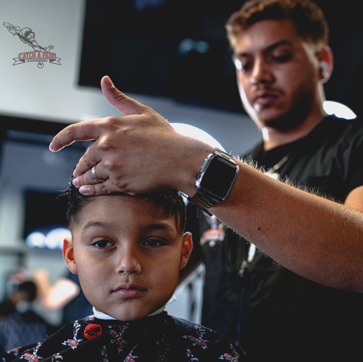Barber cutting a child's hair in a salon.