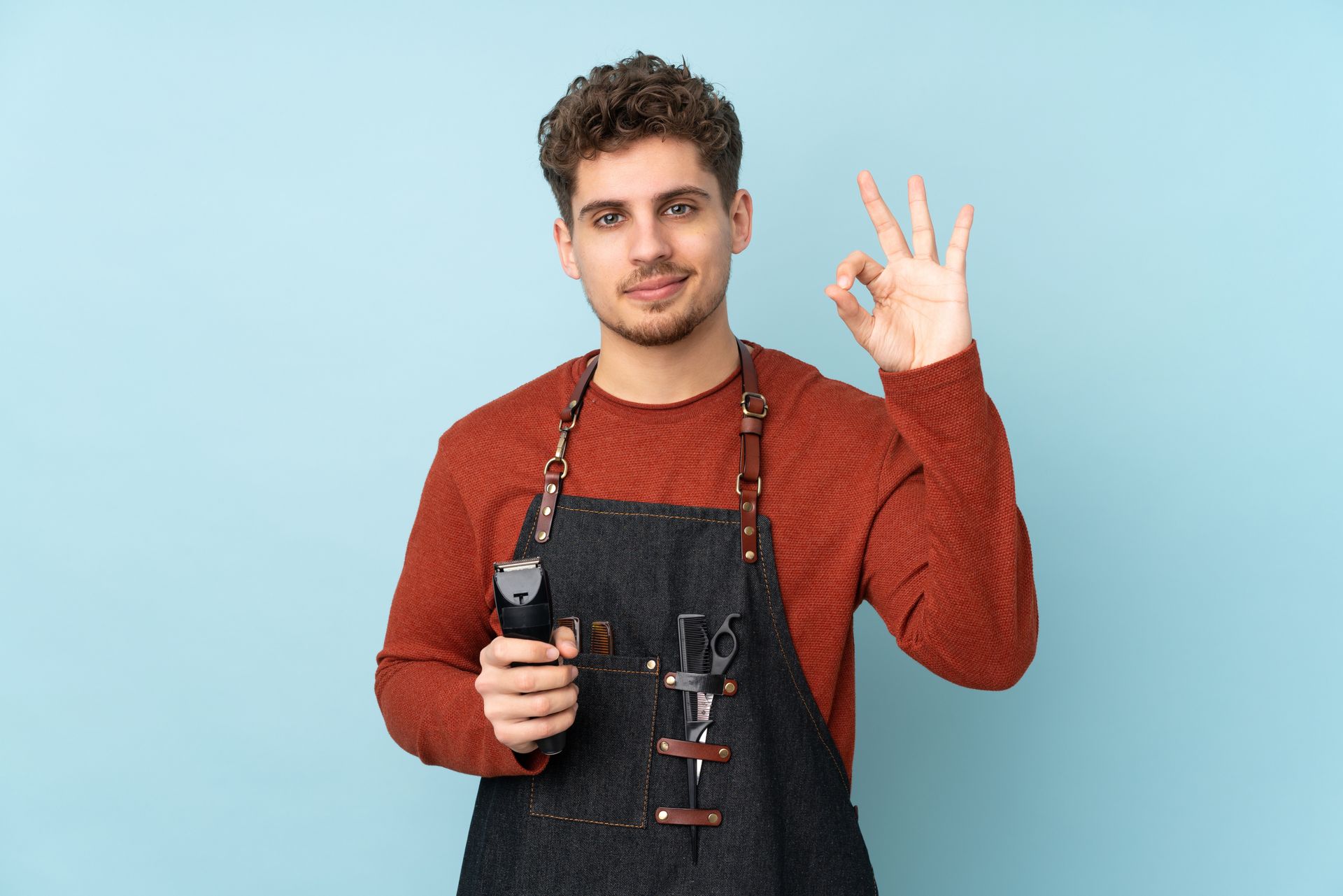 A barber with curly hair holds clippers, giving an