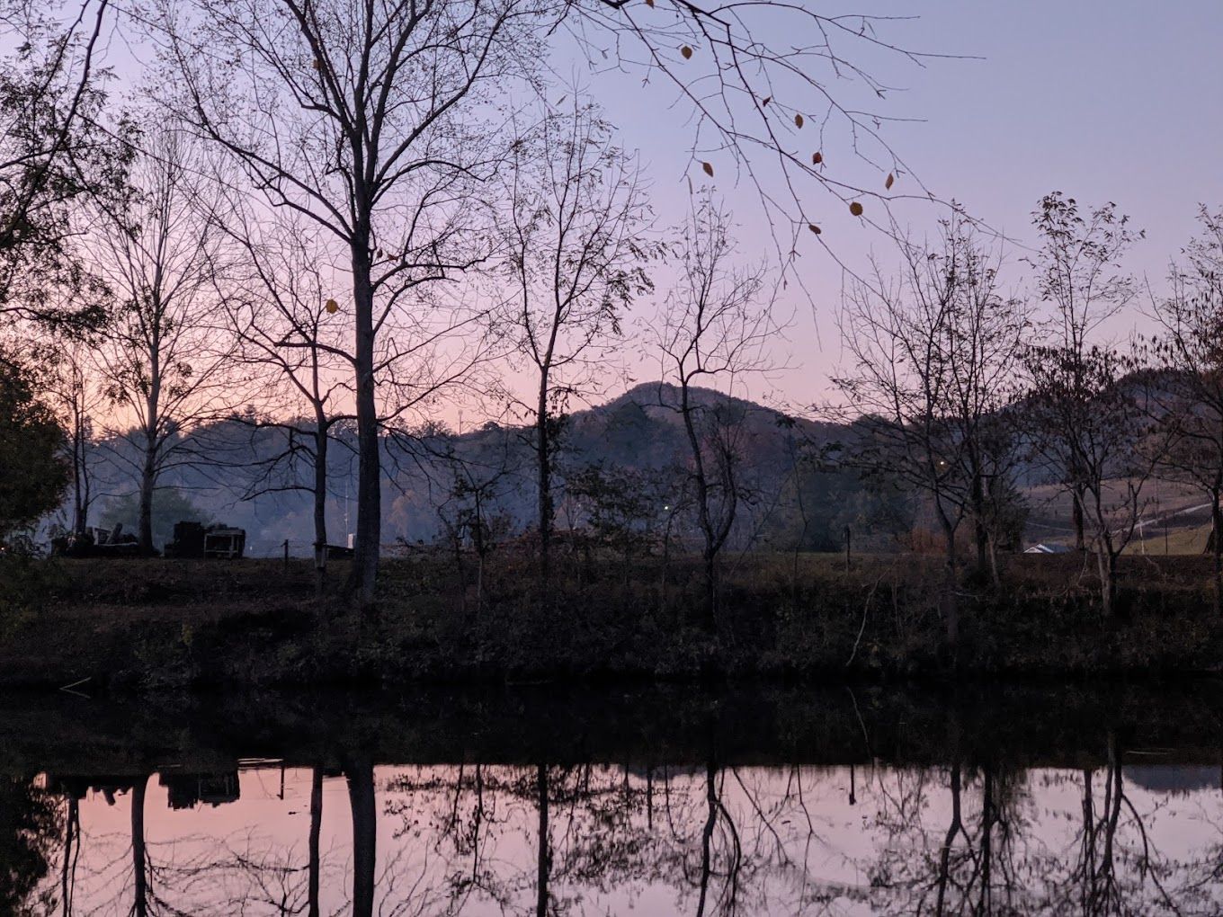 A lake with trees and mountains in the background at sunset