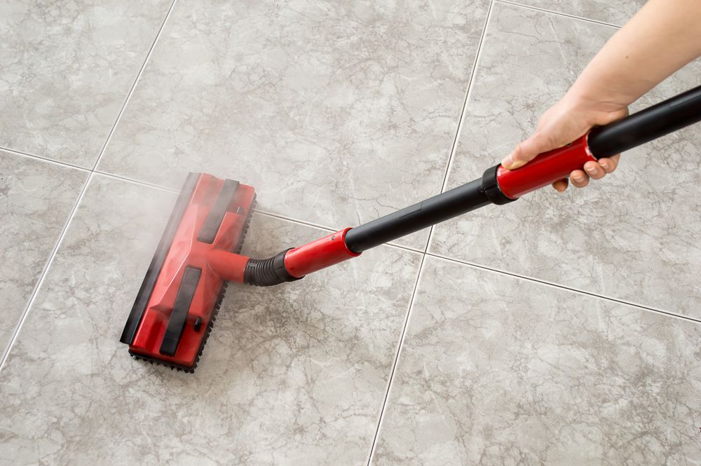 A Hand Using a Red Steam Mop — Cyclone City Cleaners In Winnellie, NT