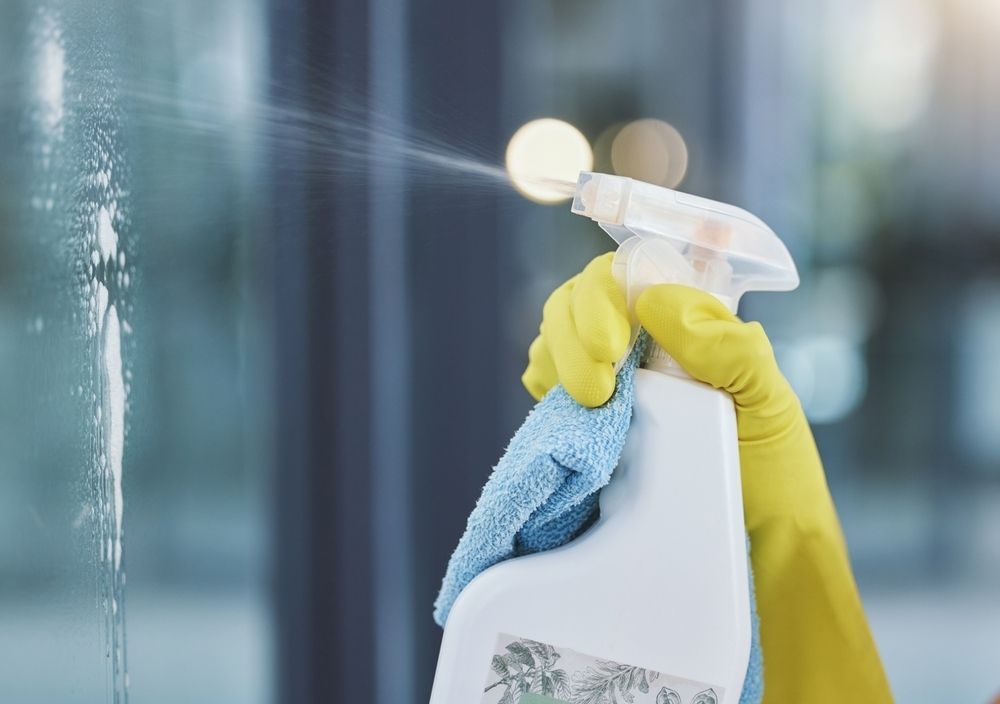 A Gloved Hand Sprays Cleaner From a White Bottle — Cyclone City Cleaners In Winnellie, NT