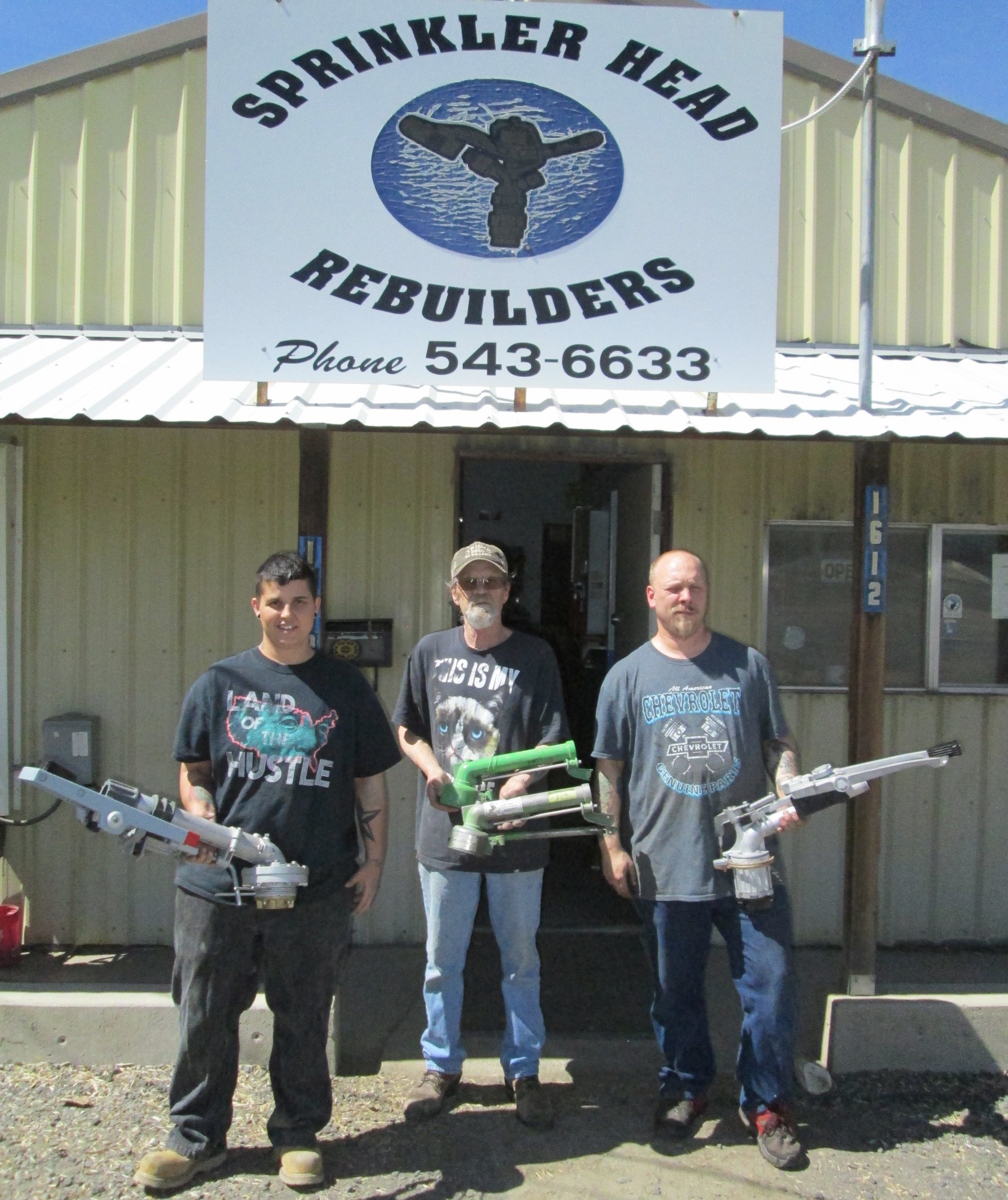 Three men standing in front of a sign that says sprinkler head rebuilders