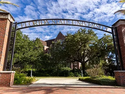 Florida State University entrance archway with brick columns and building in the background.