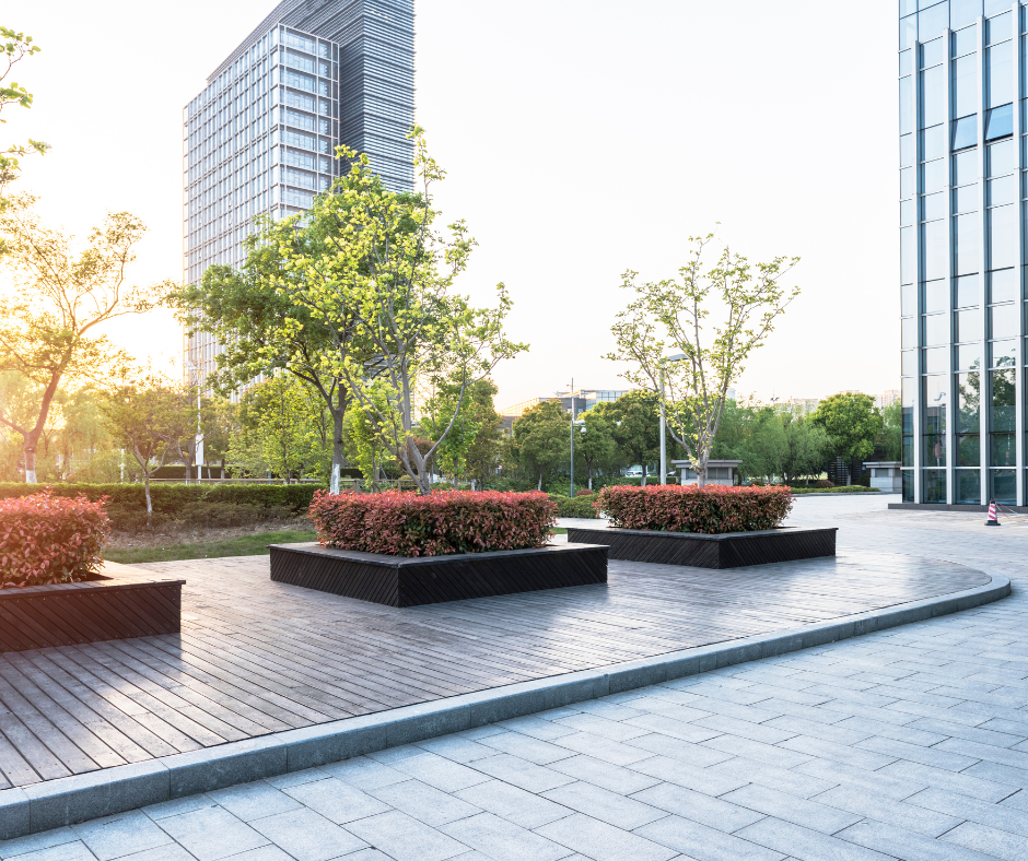 A row of planters on a sidewalk in front of a tall building being maintained