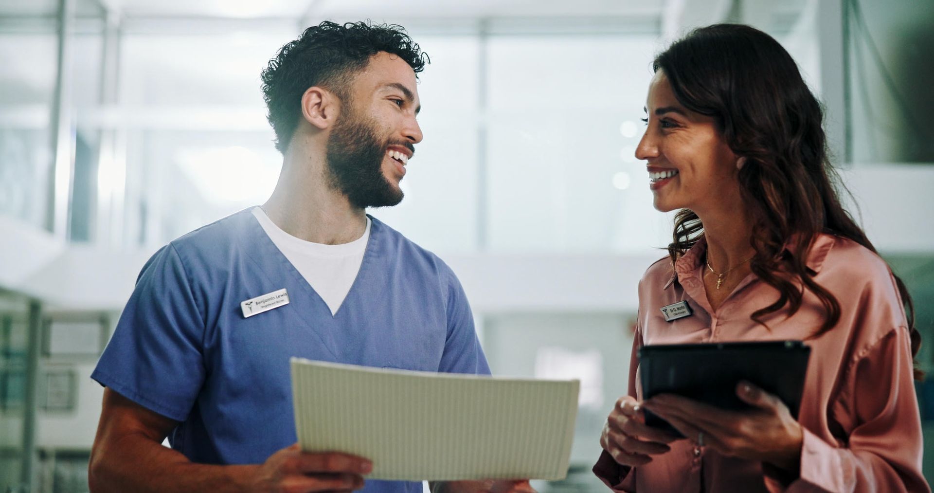 A nurse is talking to a patient in a hospital while holding a clipboard.