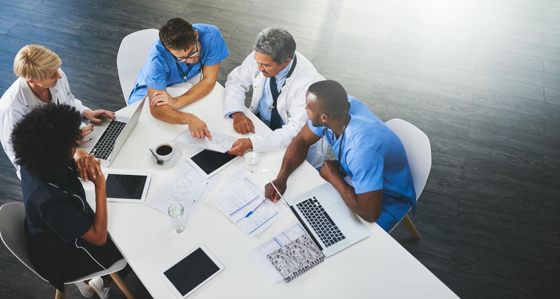 A group of doctors and nurses are sitting around a table having a meeting.