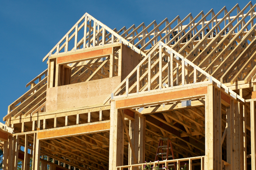 A large wooden house is being built with a blue sky in the background.