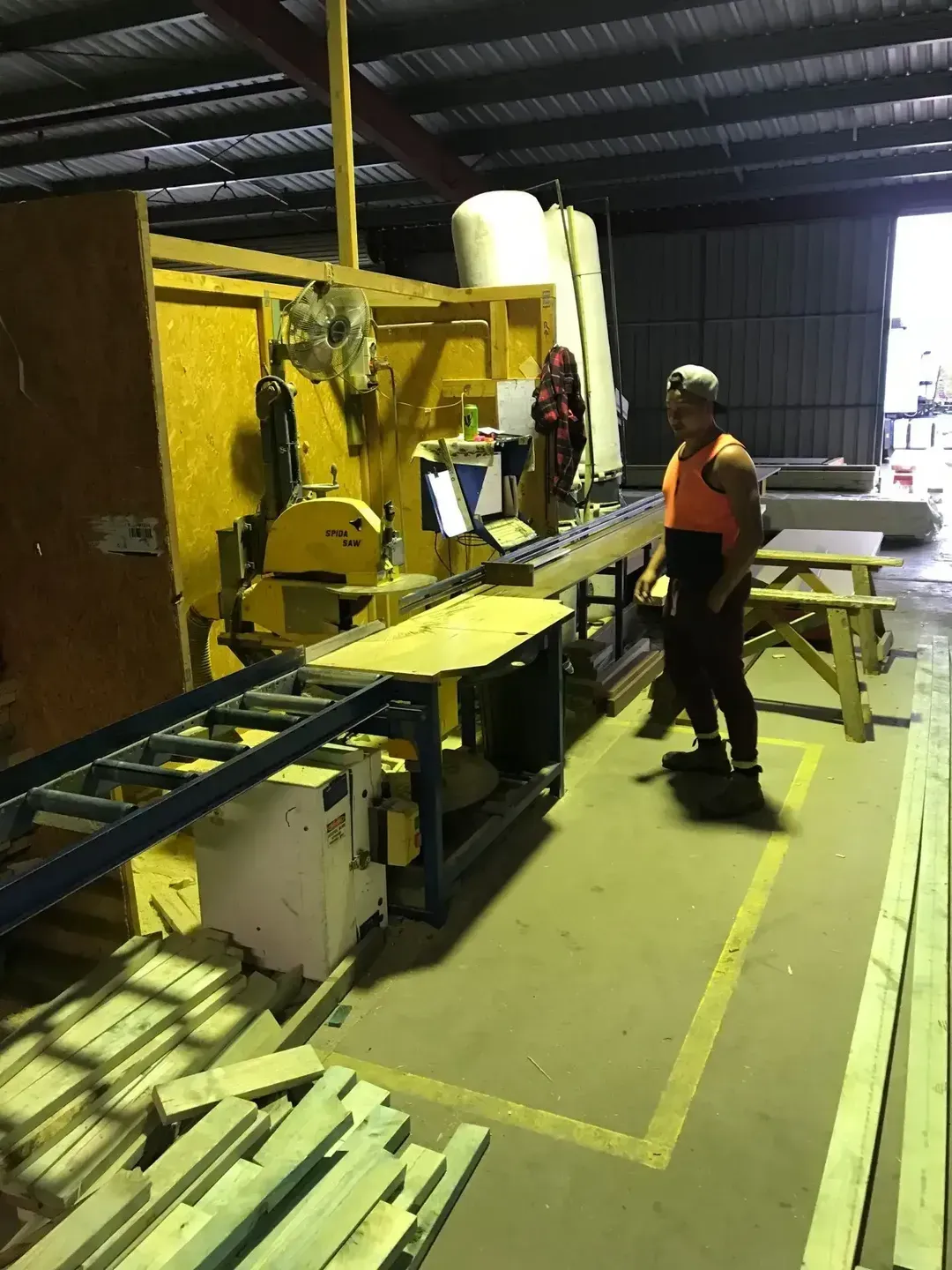 Man in Safety Vest Operates a Saw in a Workshop — Premium Trusses In South Grafton, NSW