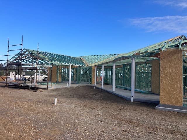 Construction of a one-story house with green wooden framing — Premium Trusses In South Grafton, NSW