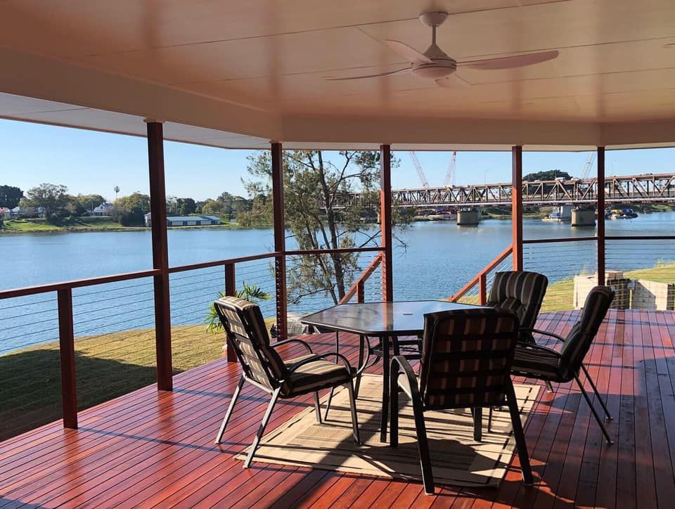 Deck overlooking a river with table, chairs, and bridge — Premium Trusses In South Grafton, NSW