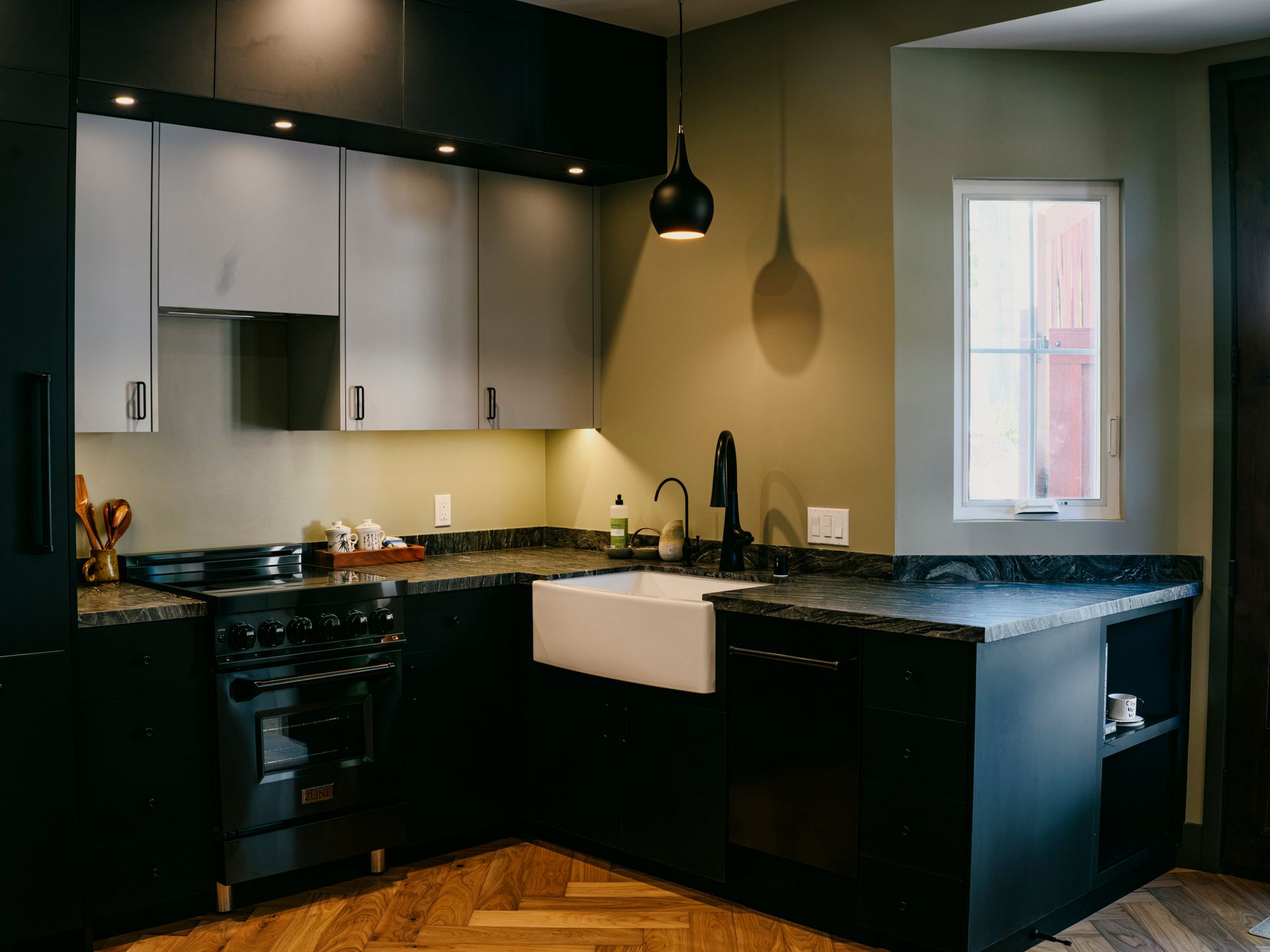 Modern kitchen with dark cabinets, light gray upper cabinets, and a white farmhouse sink.