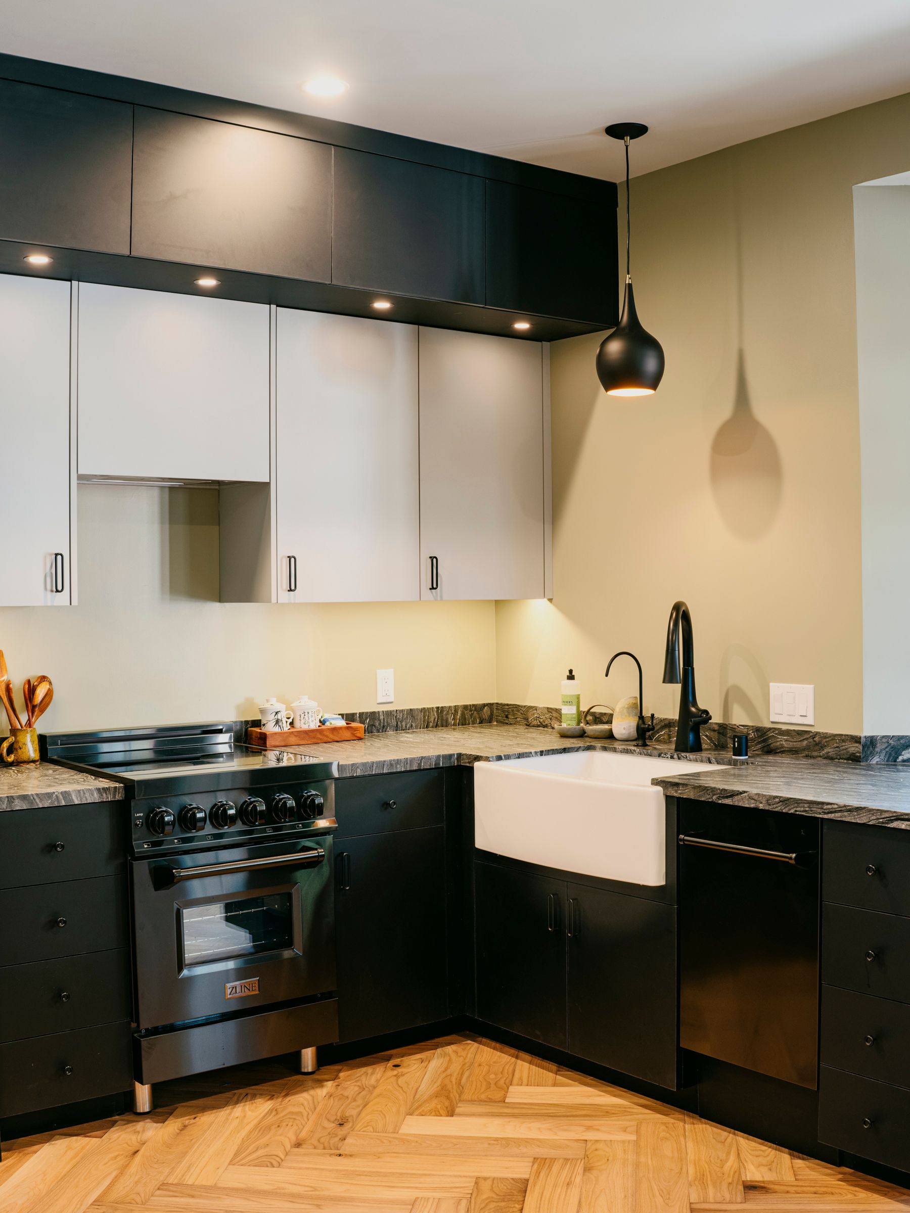 Modern kitchen with black and white cabinets, a farmhouse sink, and a gas range.