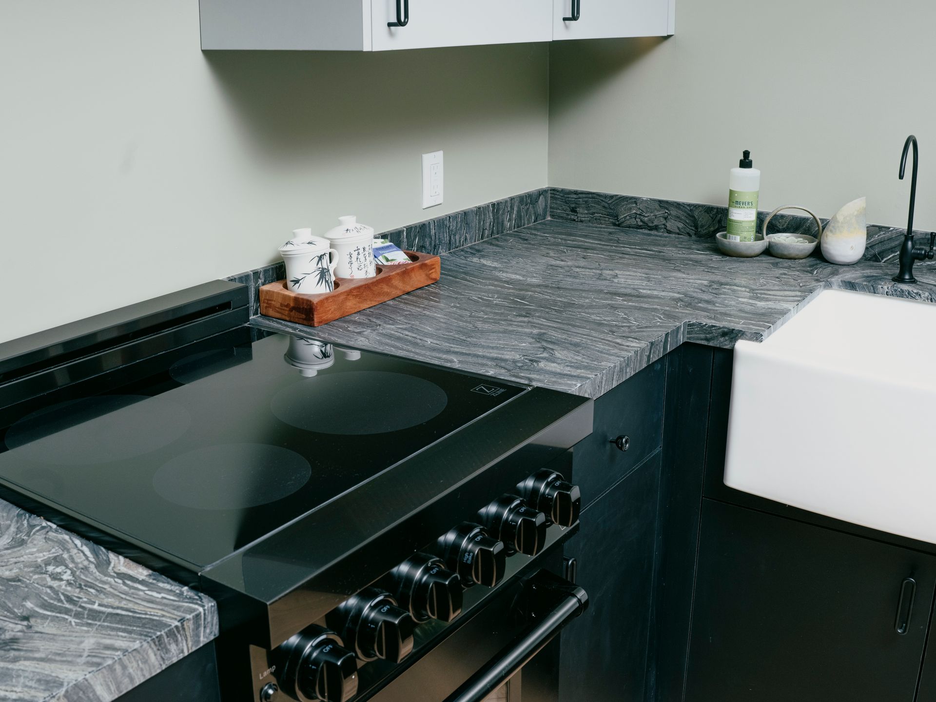 Kitchen corner with black cooktop, grey countertop, and white cabinets.
