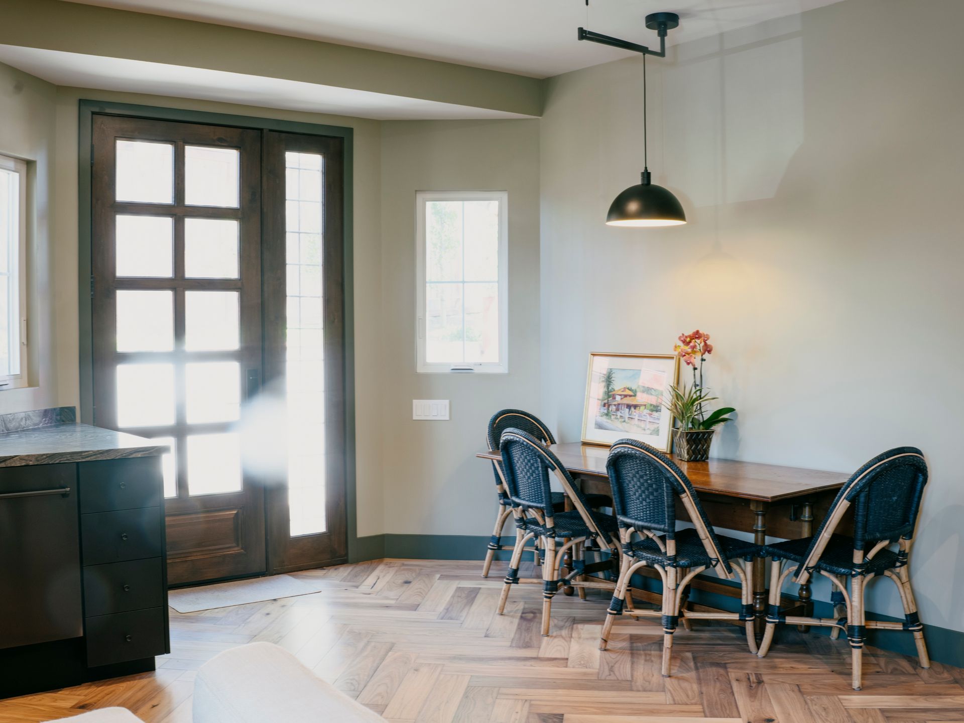 Dining room with wood table, blue chairs, and black pendant light; wood floors and door.