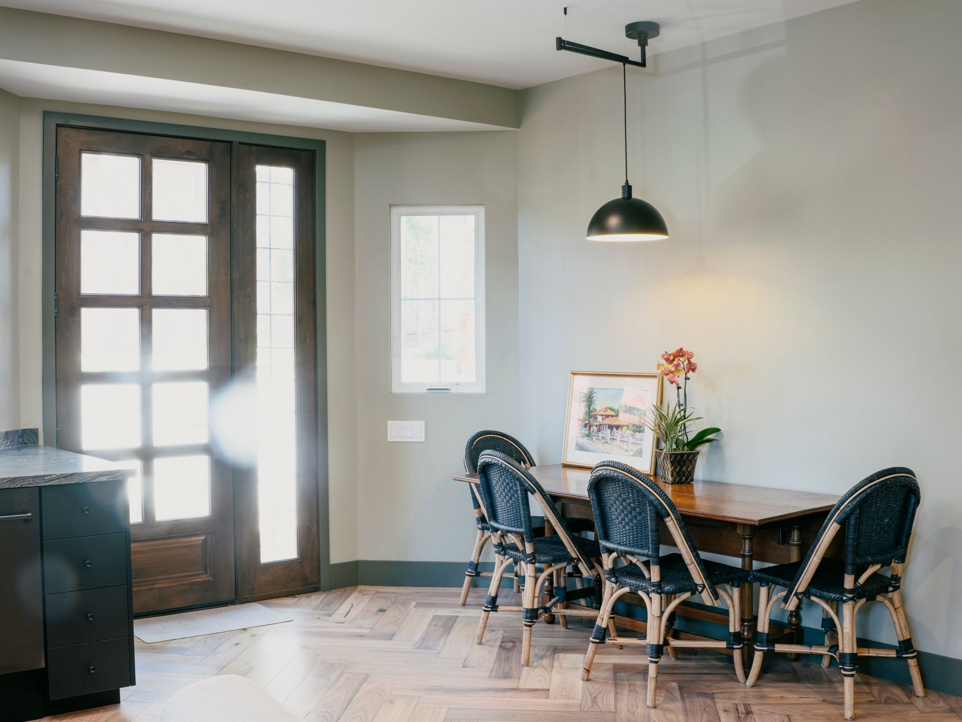 Dining area with a wooden table, four black chairs, and a black pendant light.