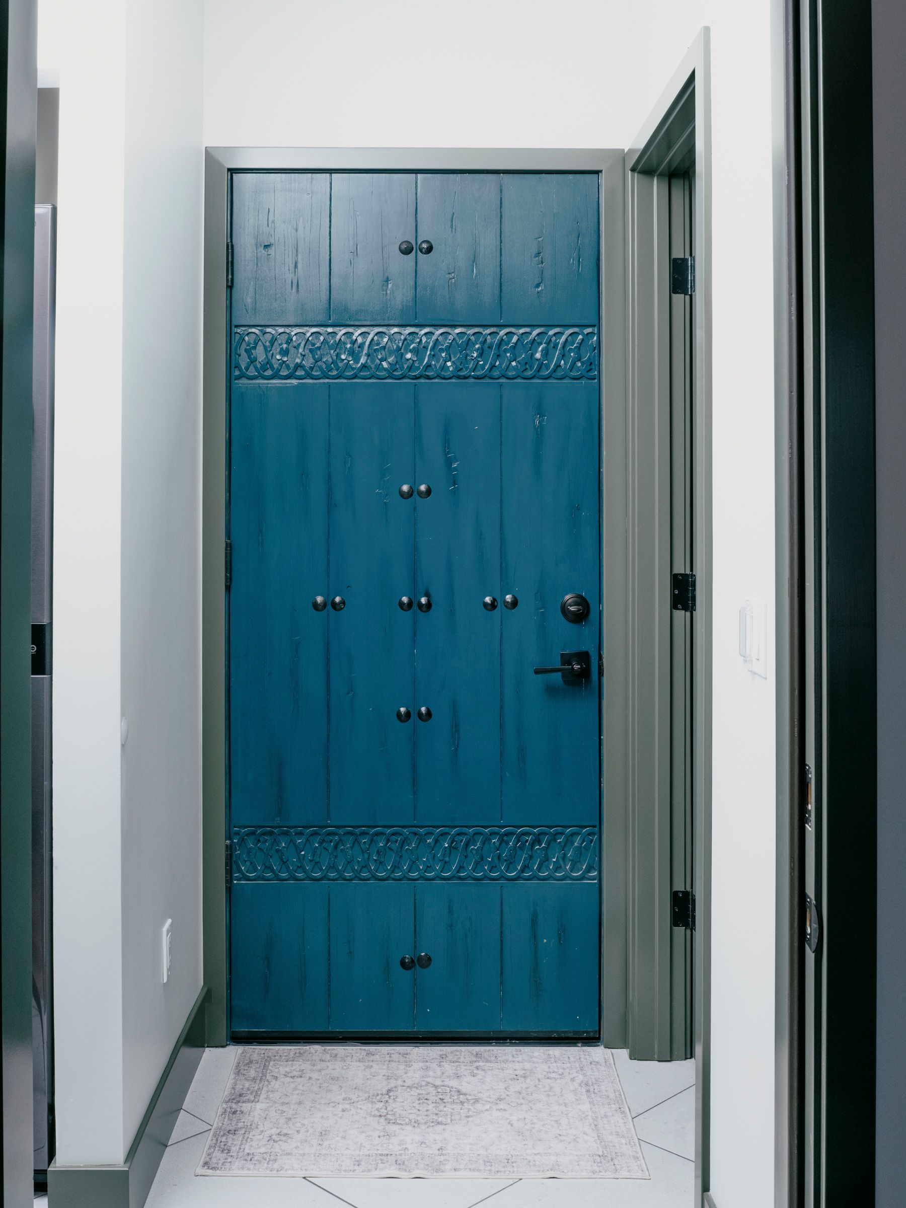 Blue wooden door with decorative metalwork in a hallway.