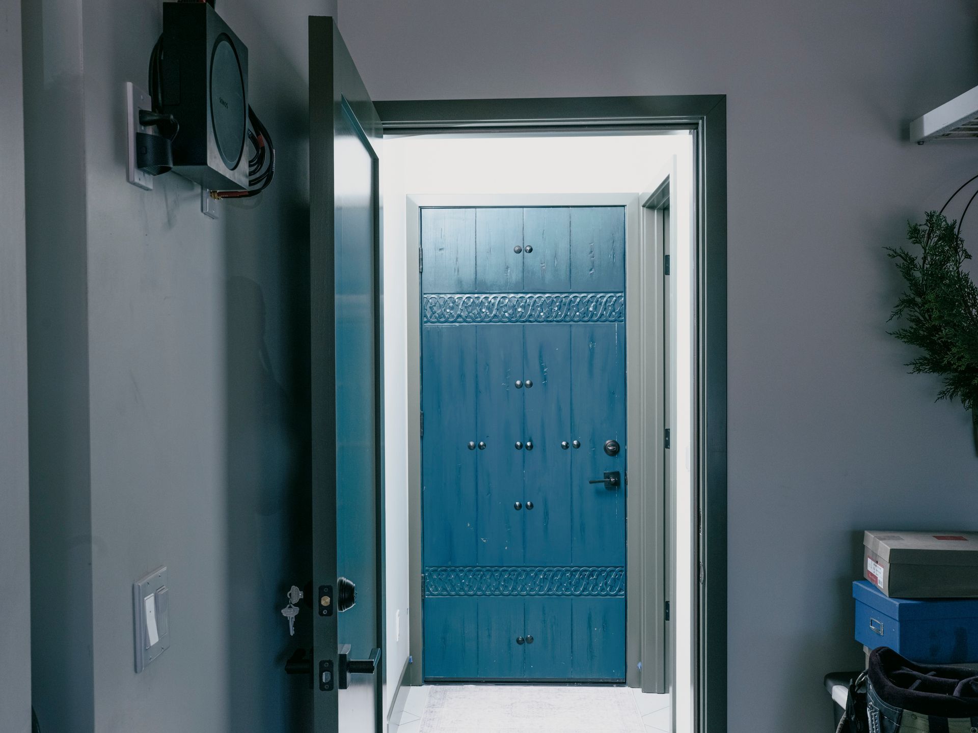 Open doorway leading to a blue door with decorative rivets, set in a gray-walled interior.