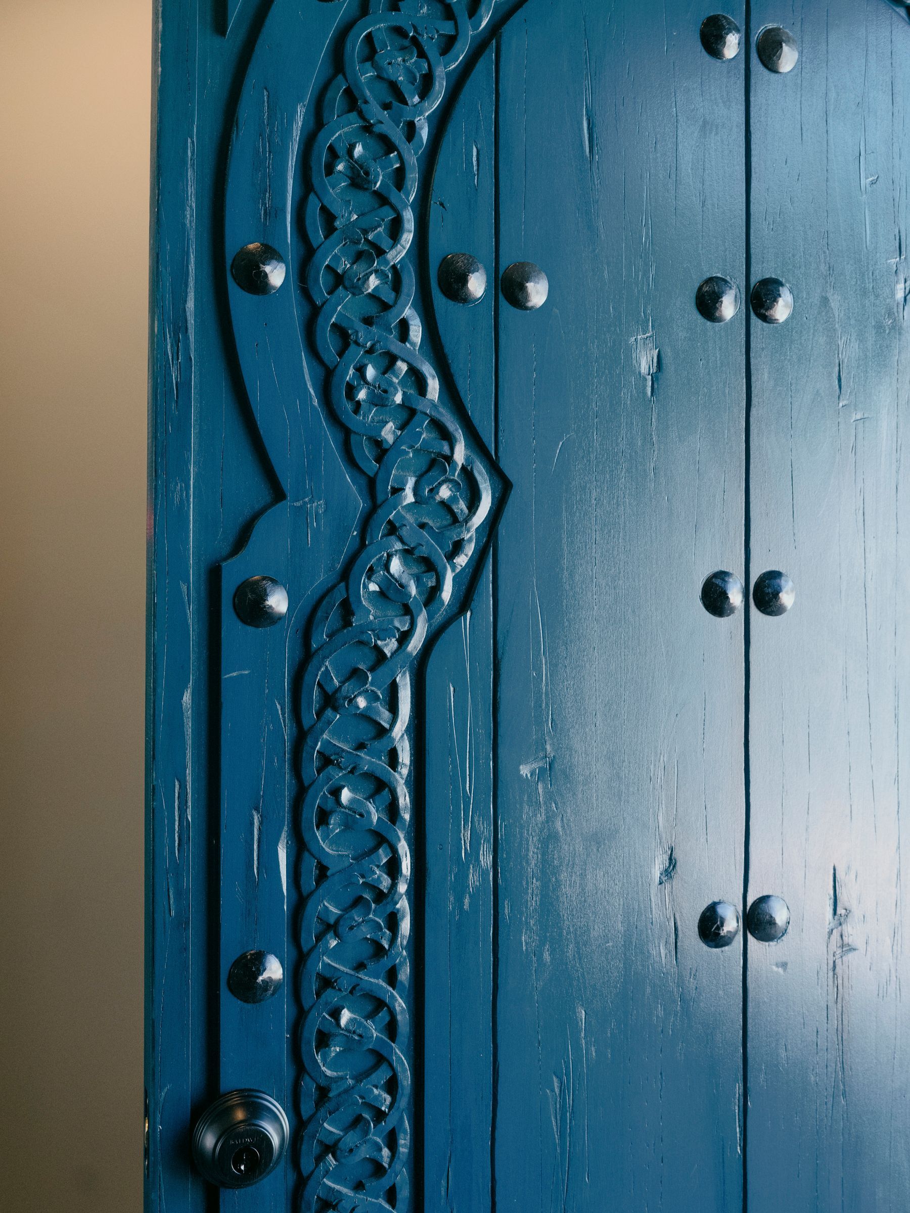 Blue wooden door with intricate carved details and metal studs.