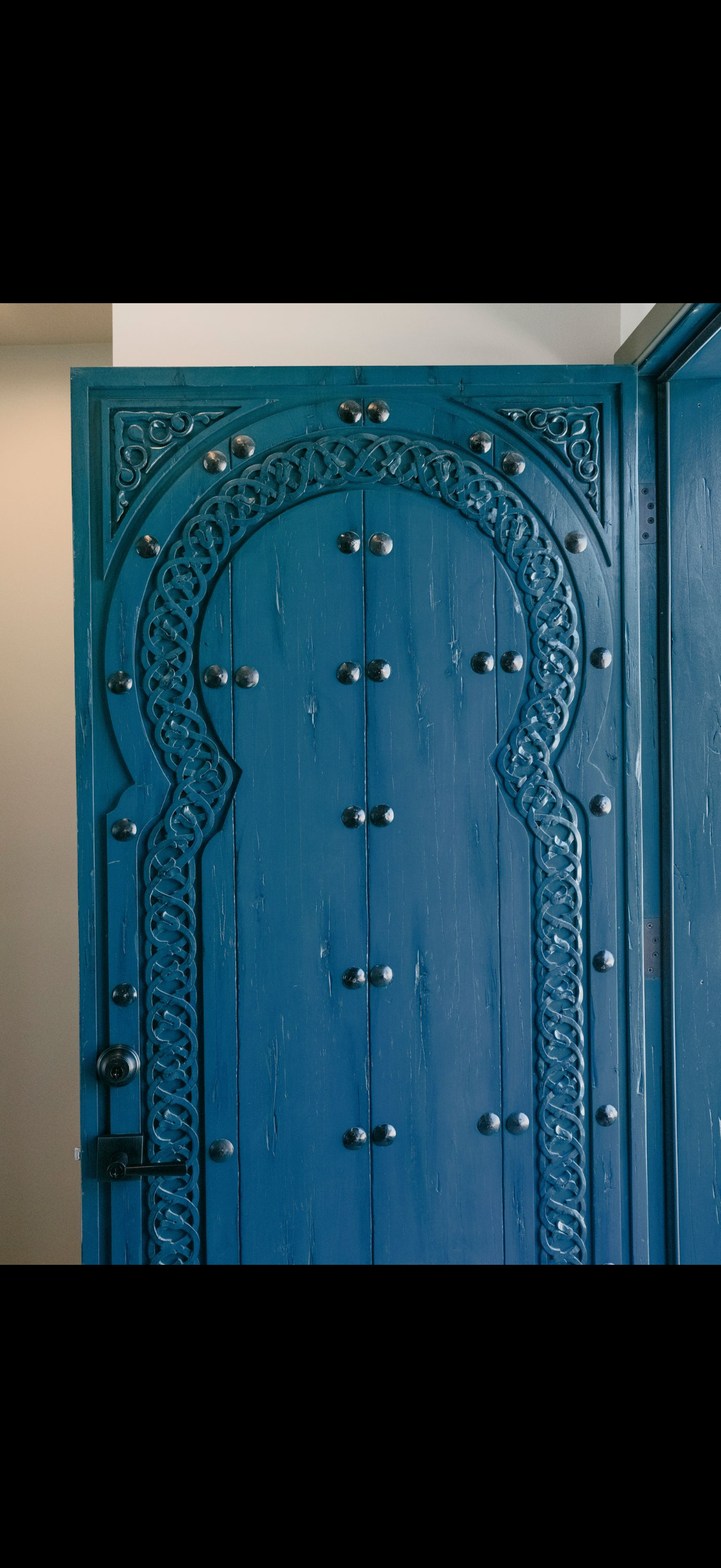 Blue ornate wooden door with Moorish arch and metal studs.