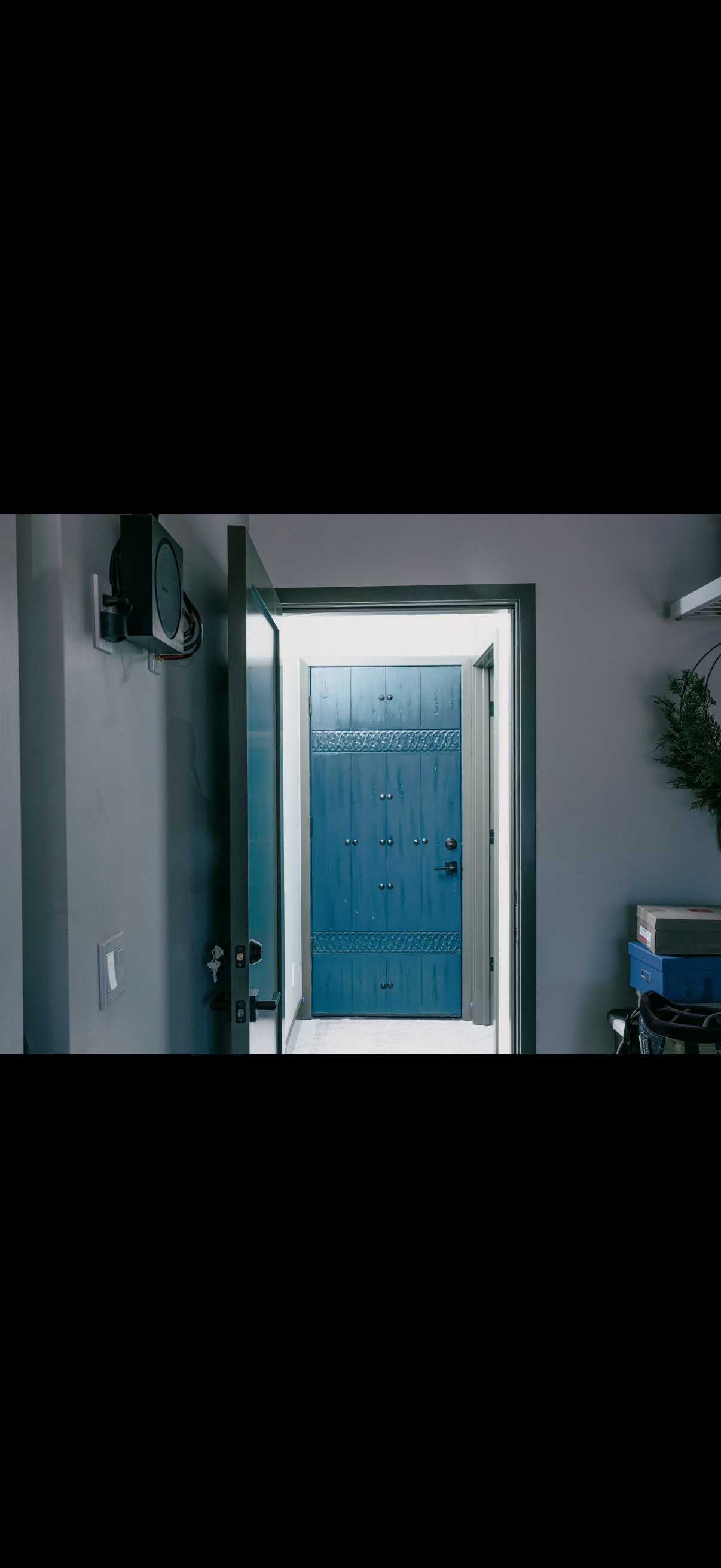 Ajar blue door, interior view, with a wall on each side and a wall-mounted object.