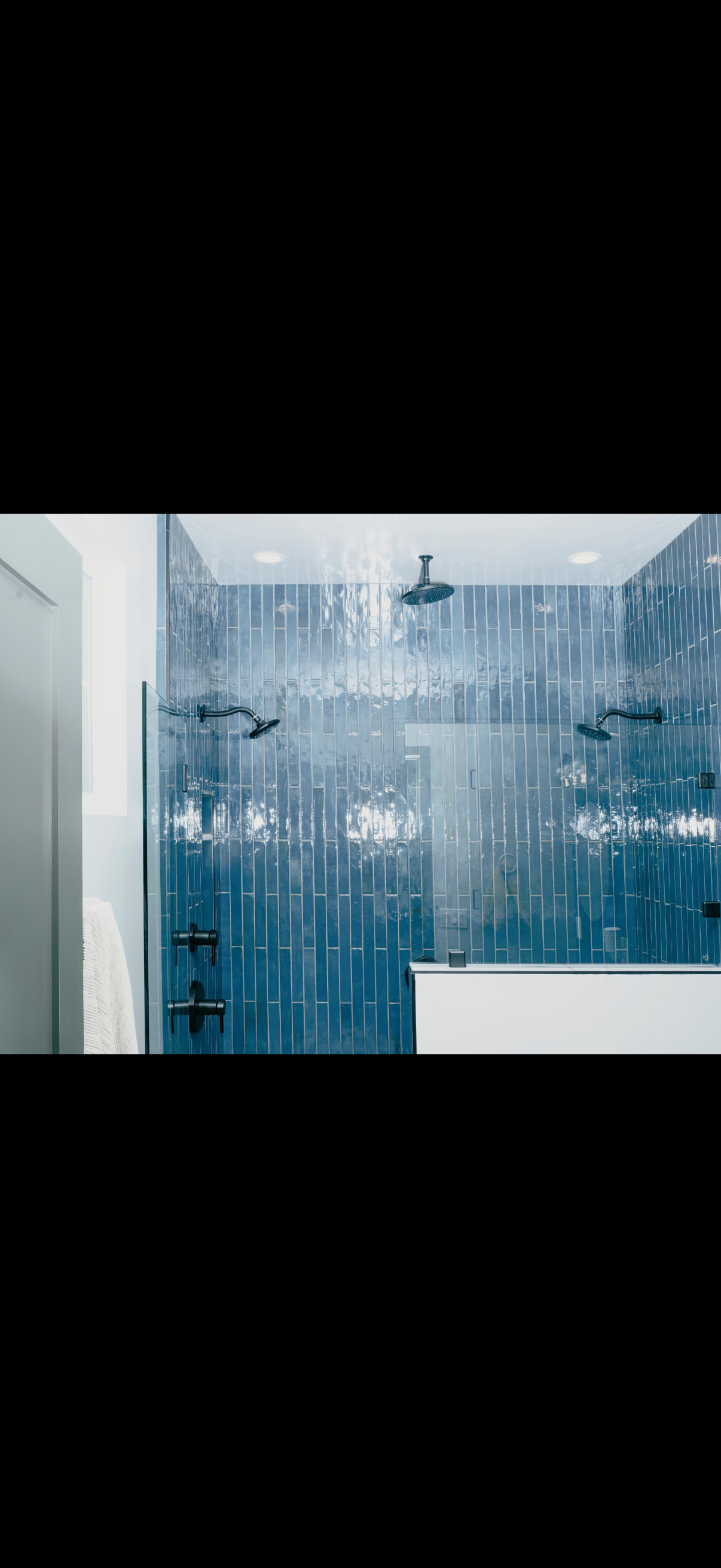 Modern blue-tiled shower with glass doors and fixtures.