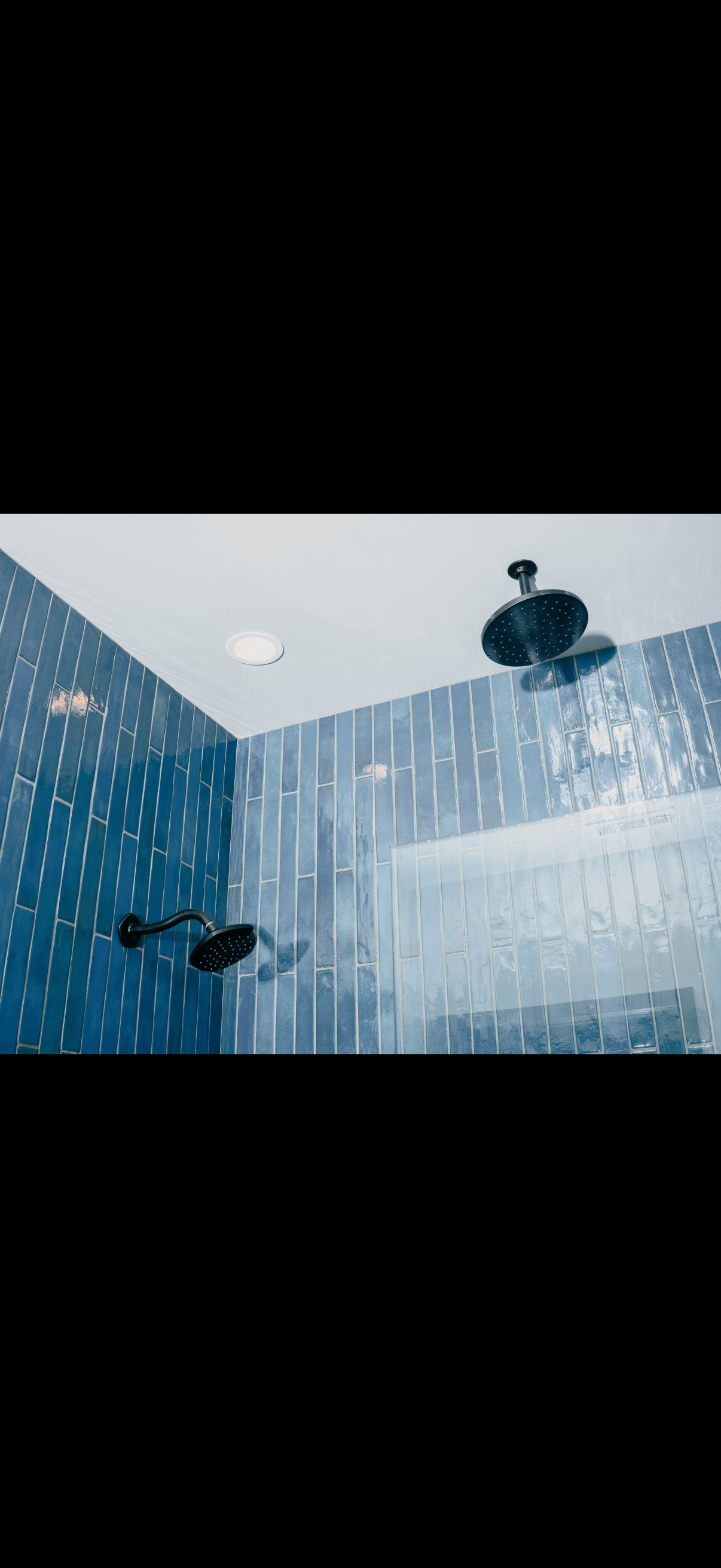 Shower with blue tiled walls, multiple showerheads.