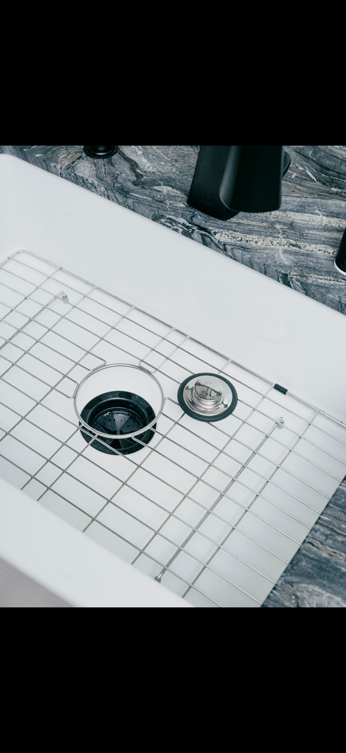 A glass with dark liquid and a sink drain cap on a checkered cloth.