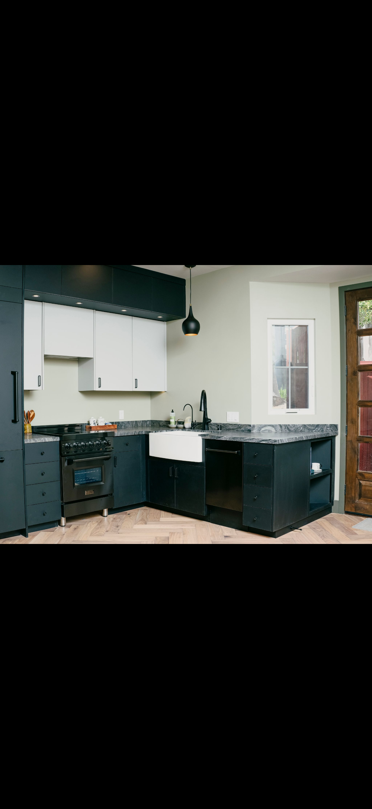 Kitchen with dark cabinets, white backsplash, and a farmhouse sink.