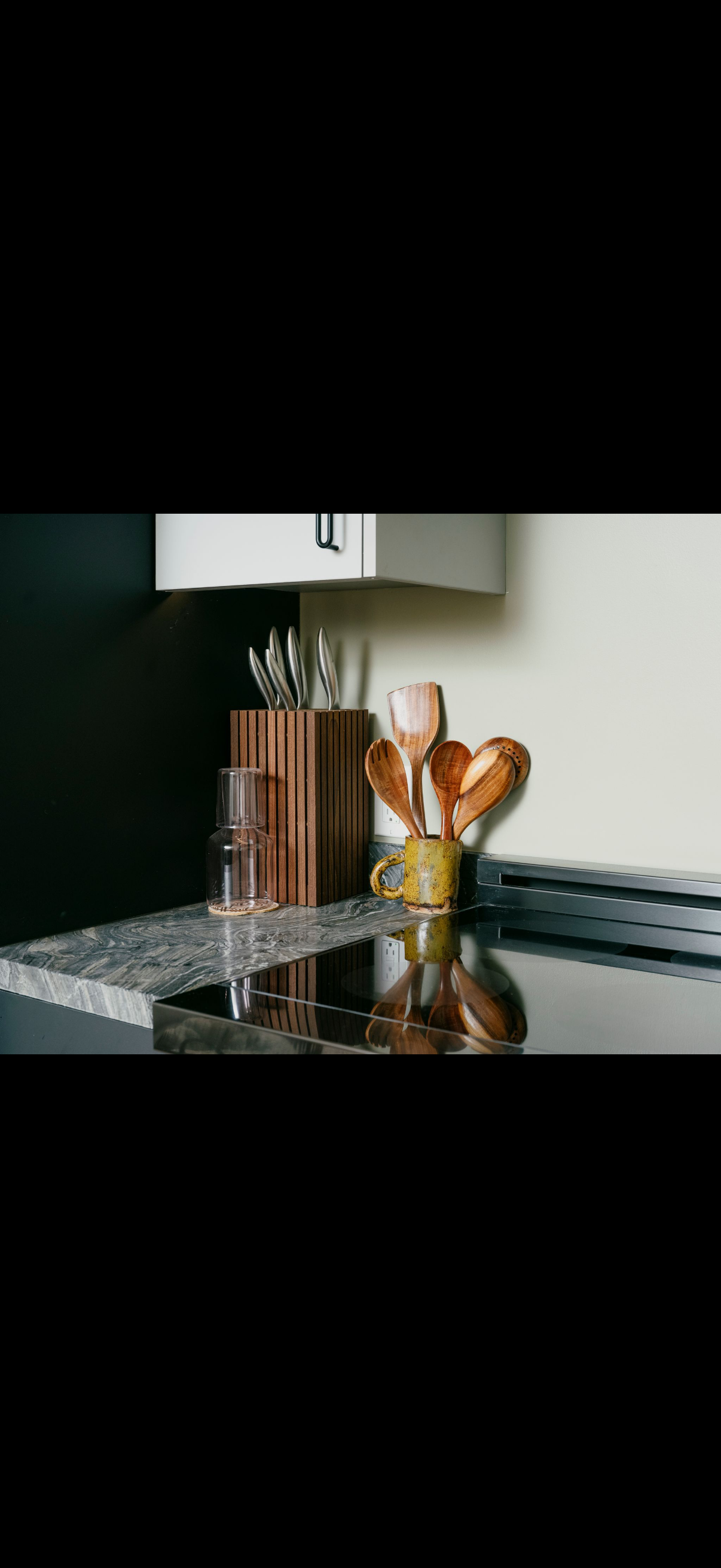 Kitchen counter with utensils, a glass, and a block for knives.