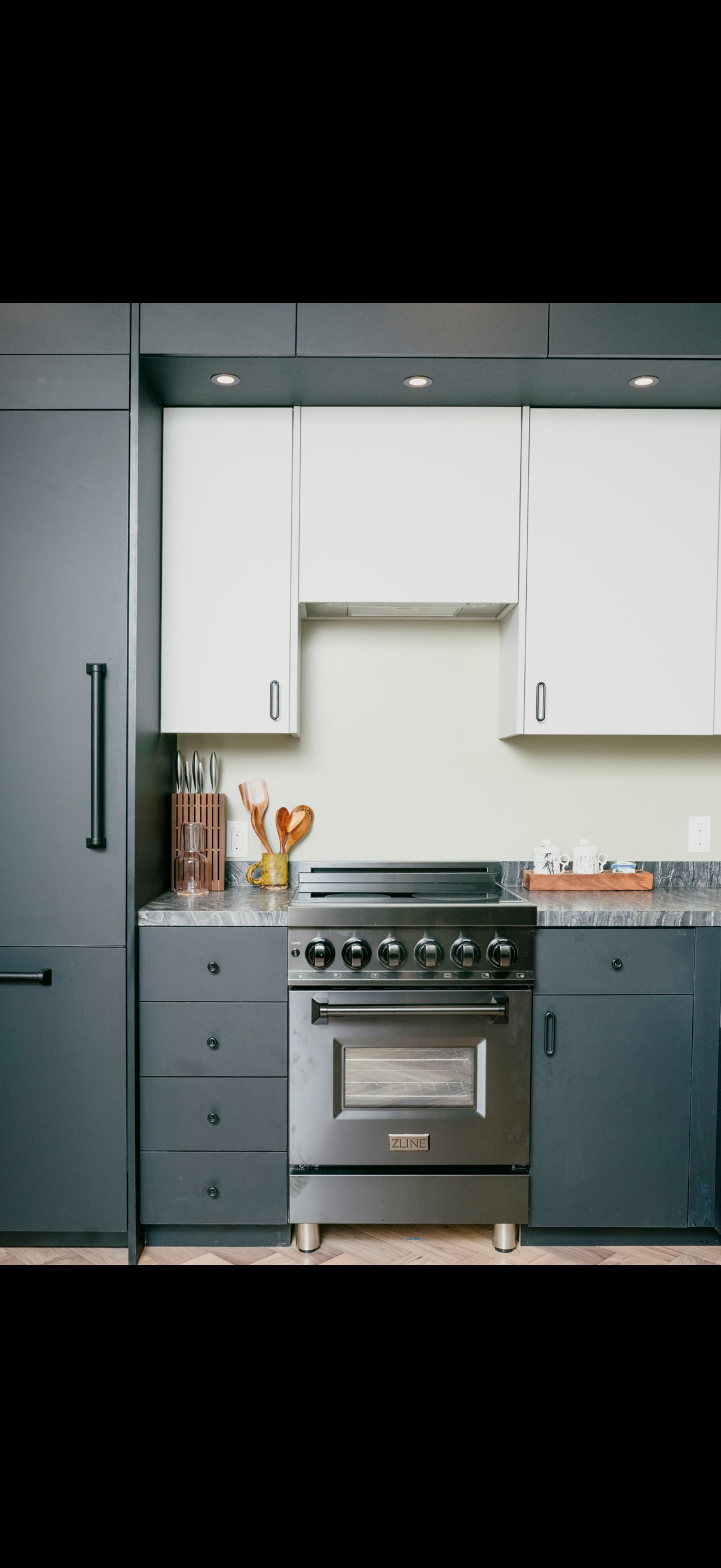 Modern kitchen with a stainless steel stove, gray cabinets, and white upper cabinets.