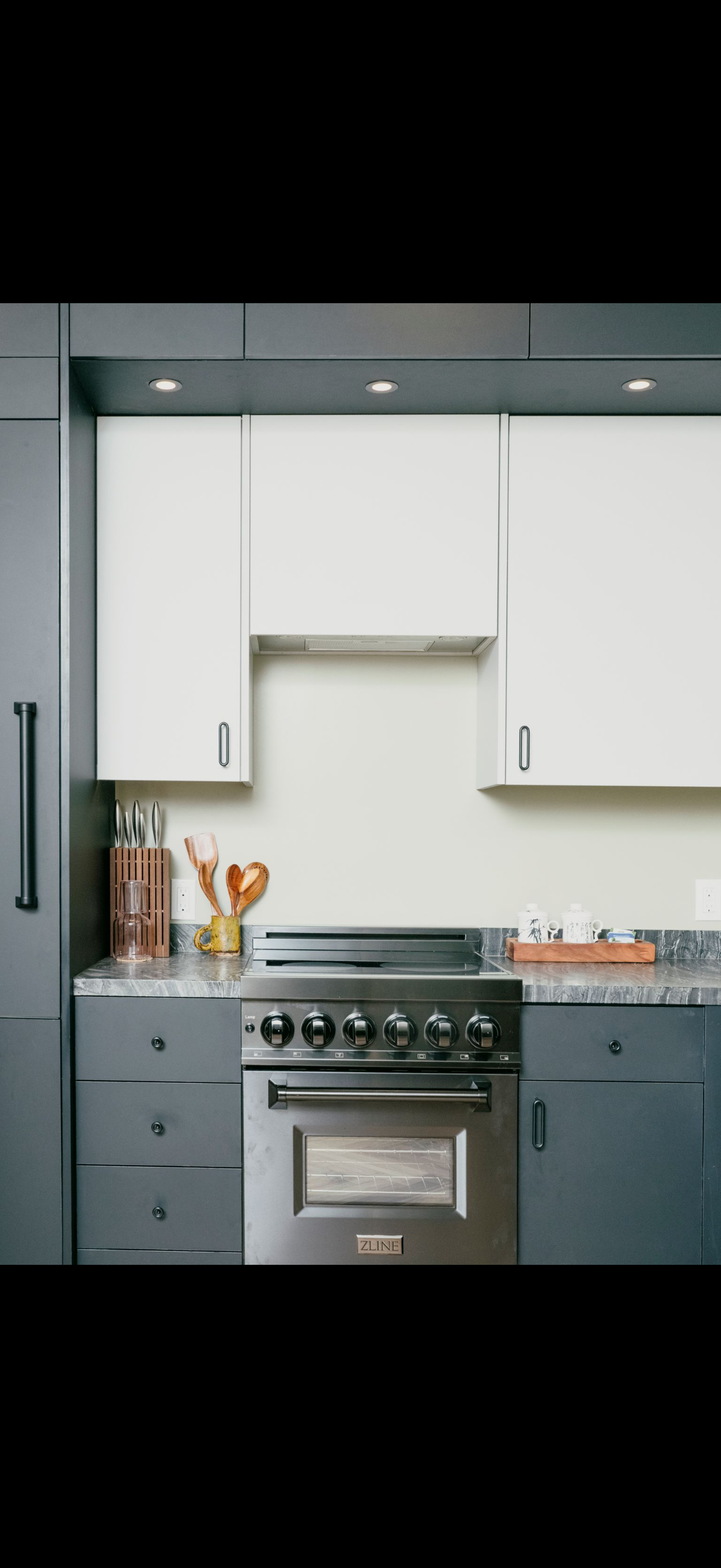 Modern kitchen with white and gray cabinets, stainless steel range, and countertop with marble effect.