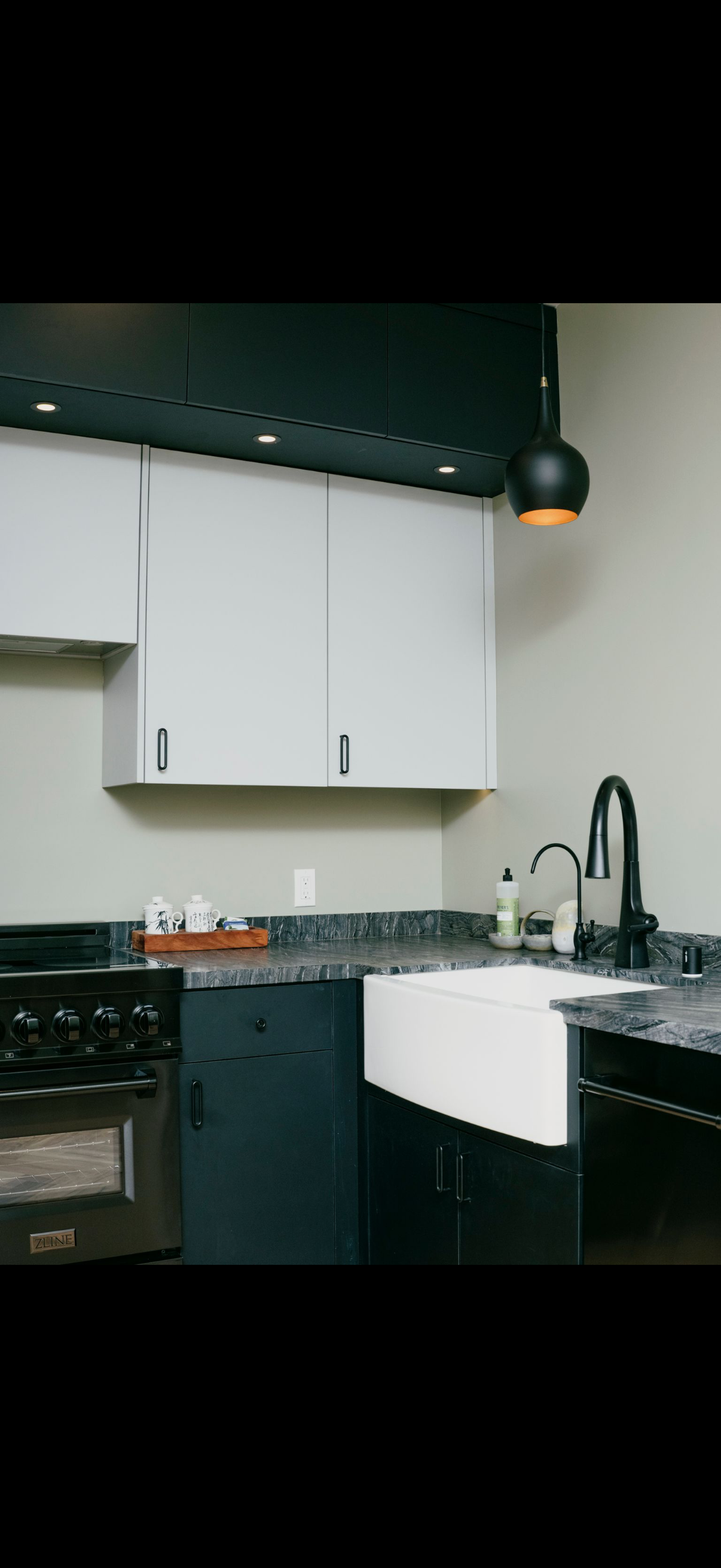 Kitchen with white cabinets, black countertop, and a farmhouse sink.