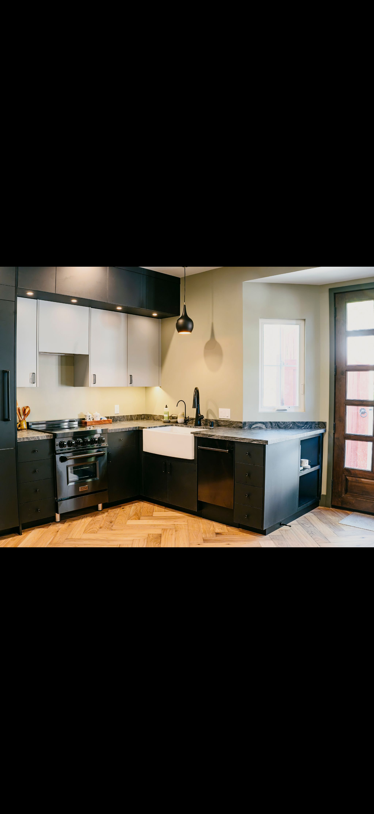 Modern kitchen with dark cabinets, light countertops, and a farmhouse sink.
