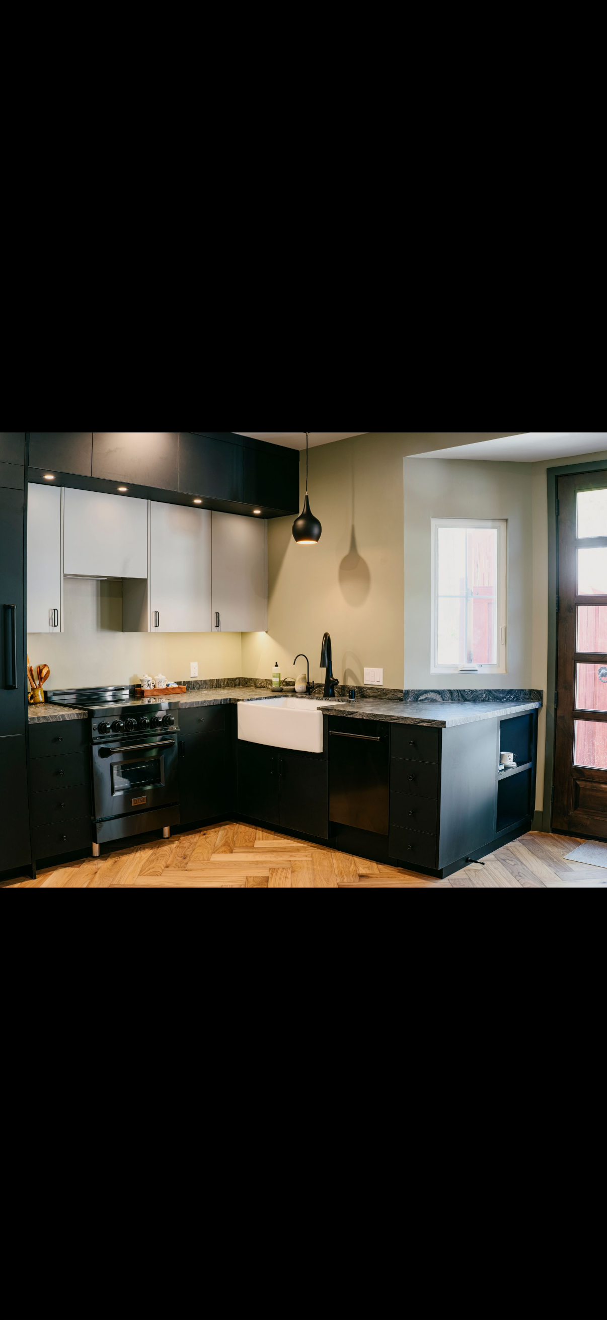 A modern kitchen with dark cabinets, a white farmhouse sink, and an island with open shelving.