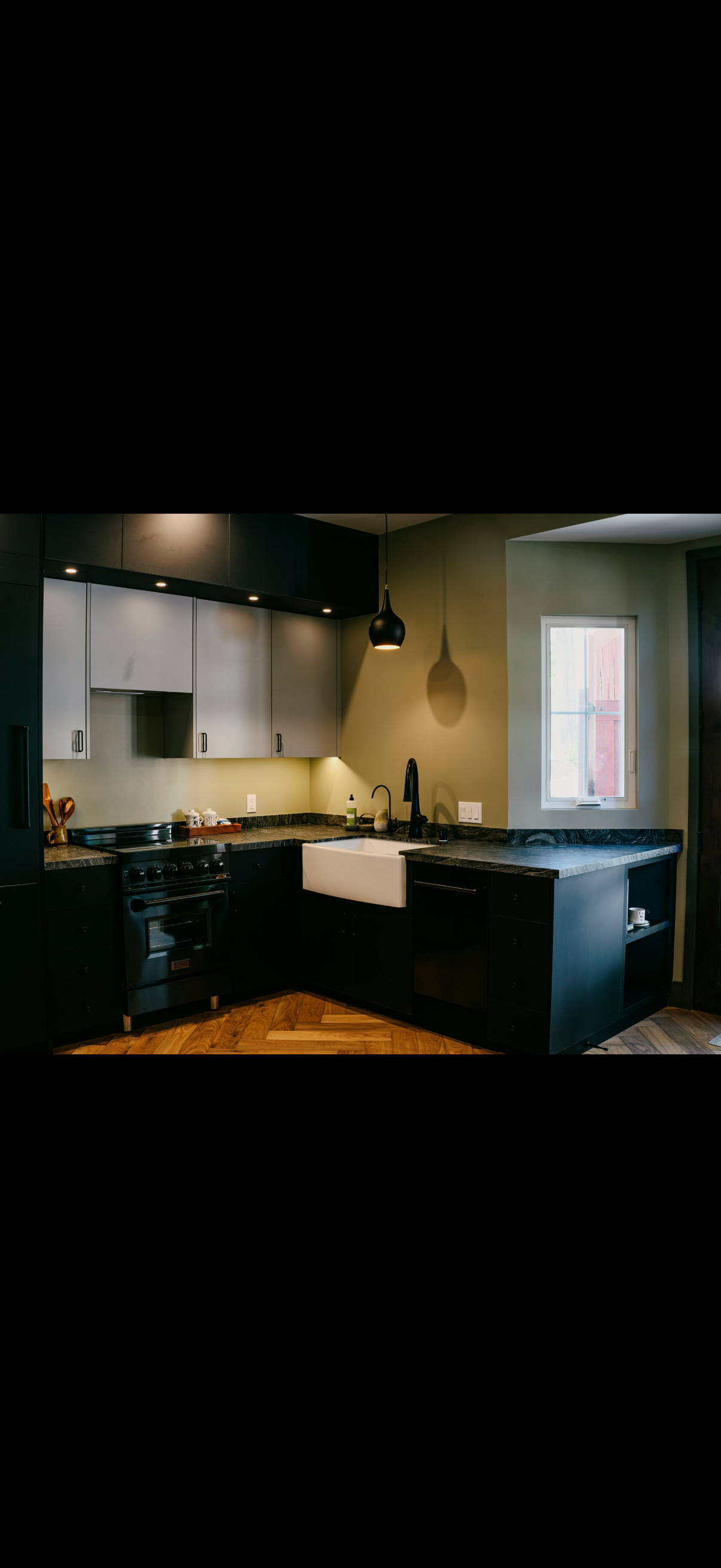 Modern kitchen with dark cabinetry, white countertops, and a farmhouse sink.